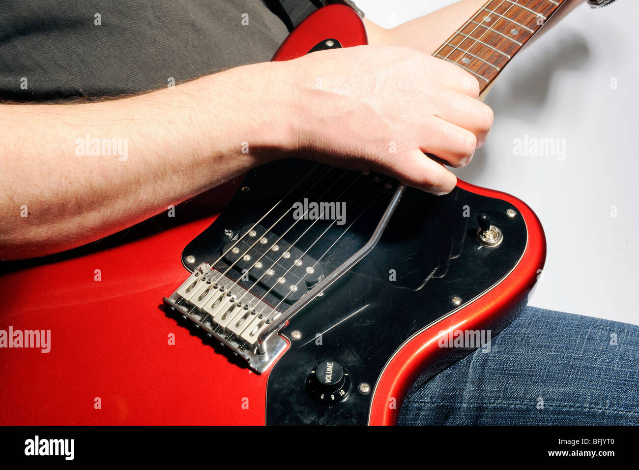 Uomo che utilizza tremelo su un rosso six string chitarra elettrica Foto Stock