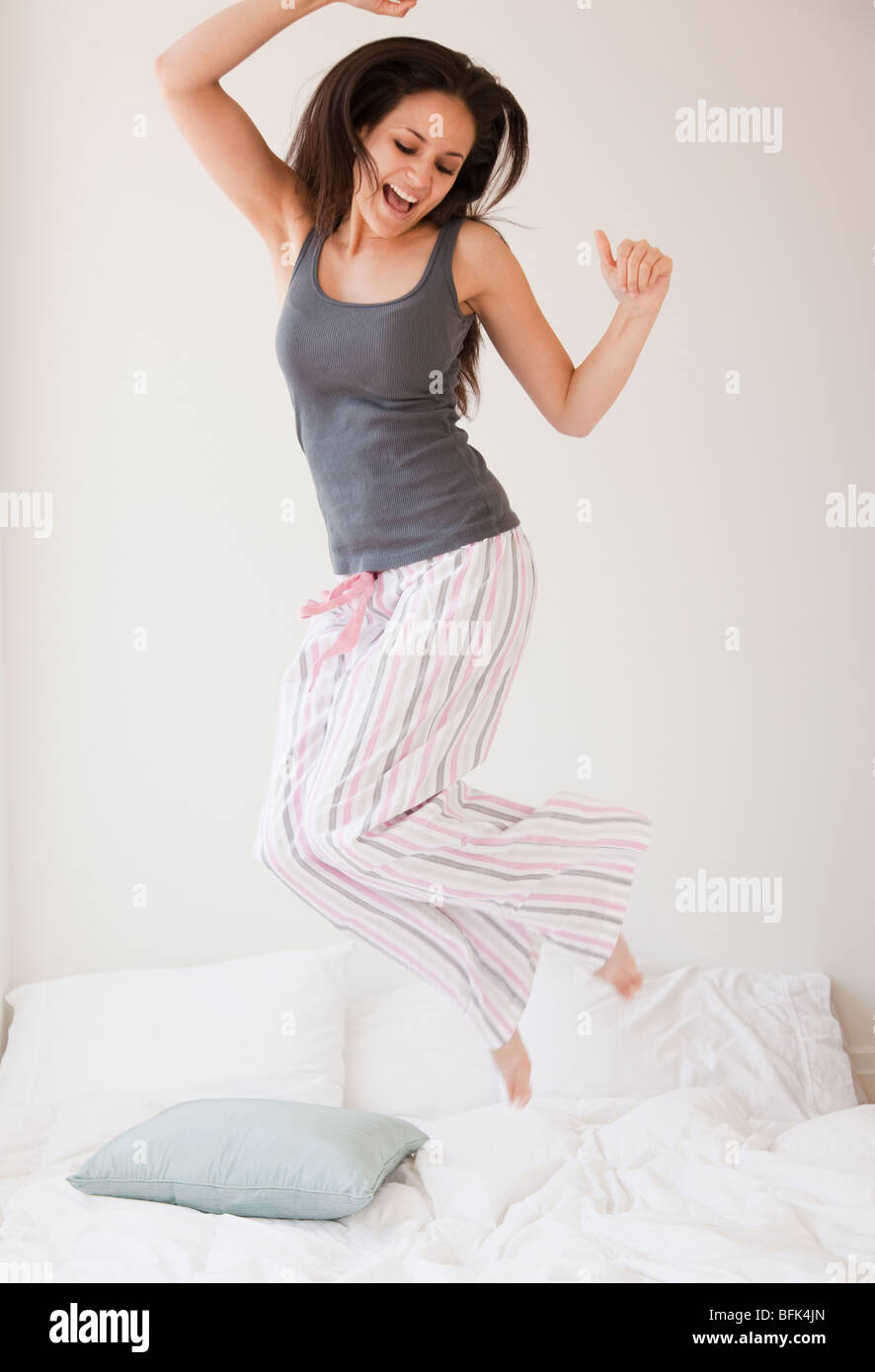 Razza mista donna saltando sul letto Foto Stock