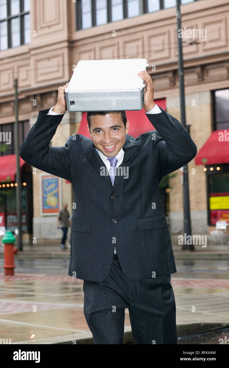 Imprenditore testa di copertura con valigetta in Rain Foto Stock
