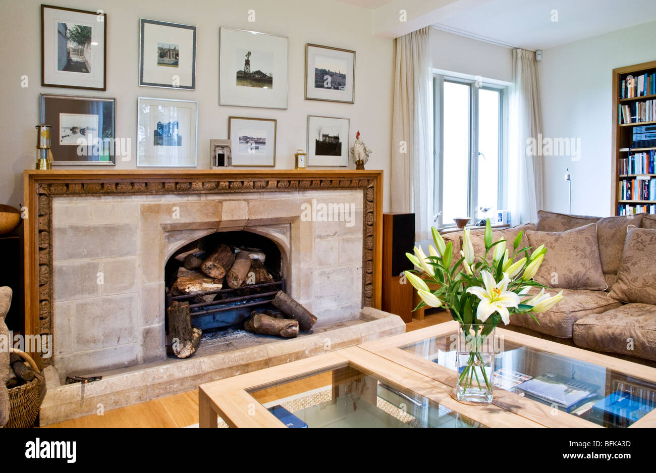 Un moderno e contemporaneo elegante soggiorno con camino in pietra e vaso di freschi gigli bianchi Foto Stock