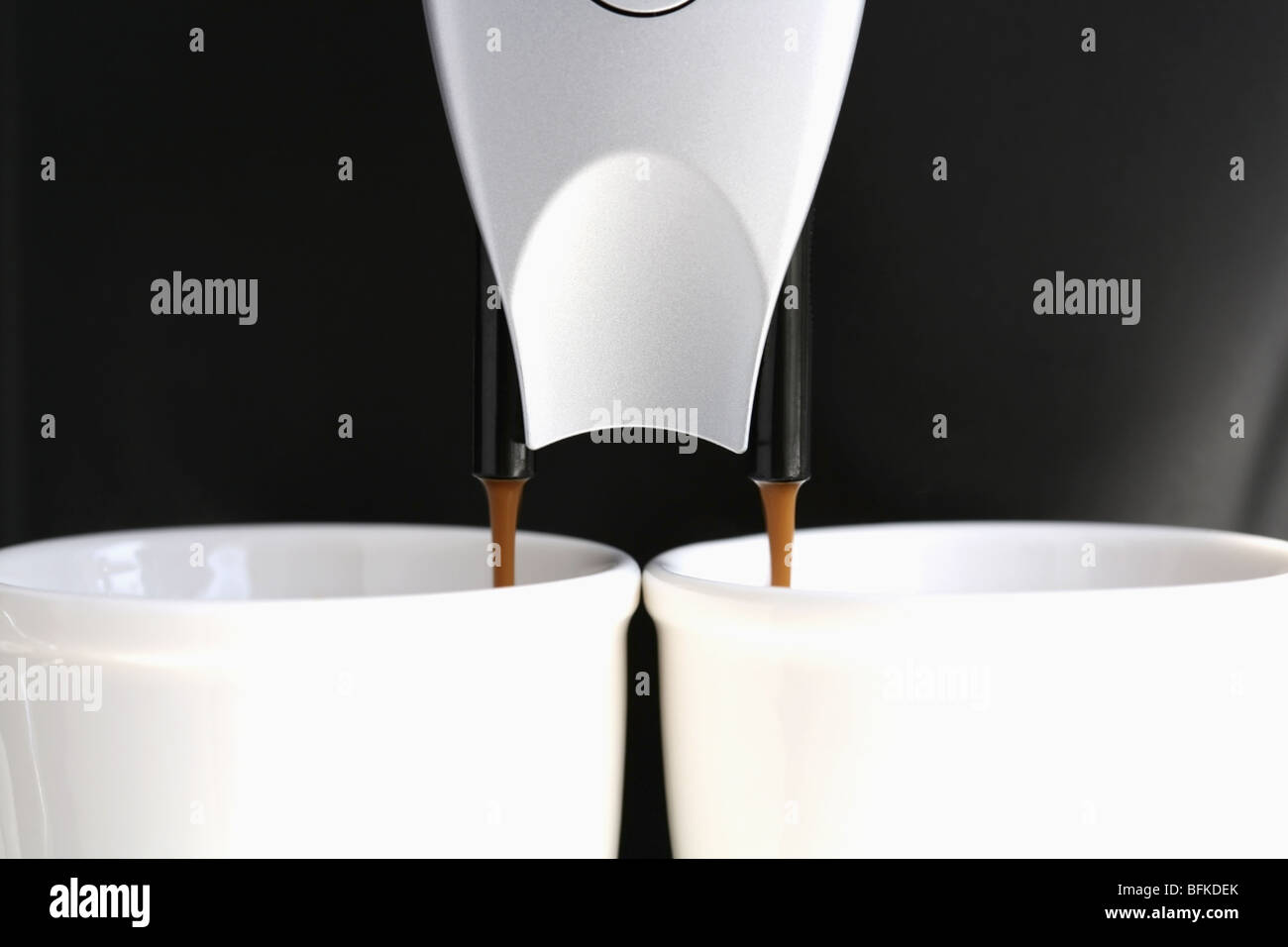 Macchina espresso versando il caffè in tazze vicino su sfondo nero Foto Stock