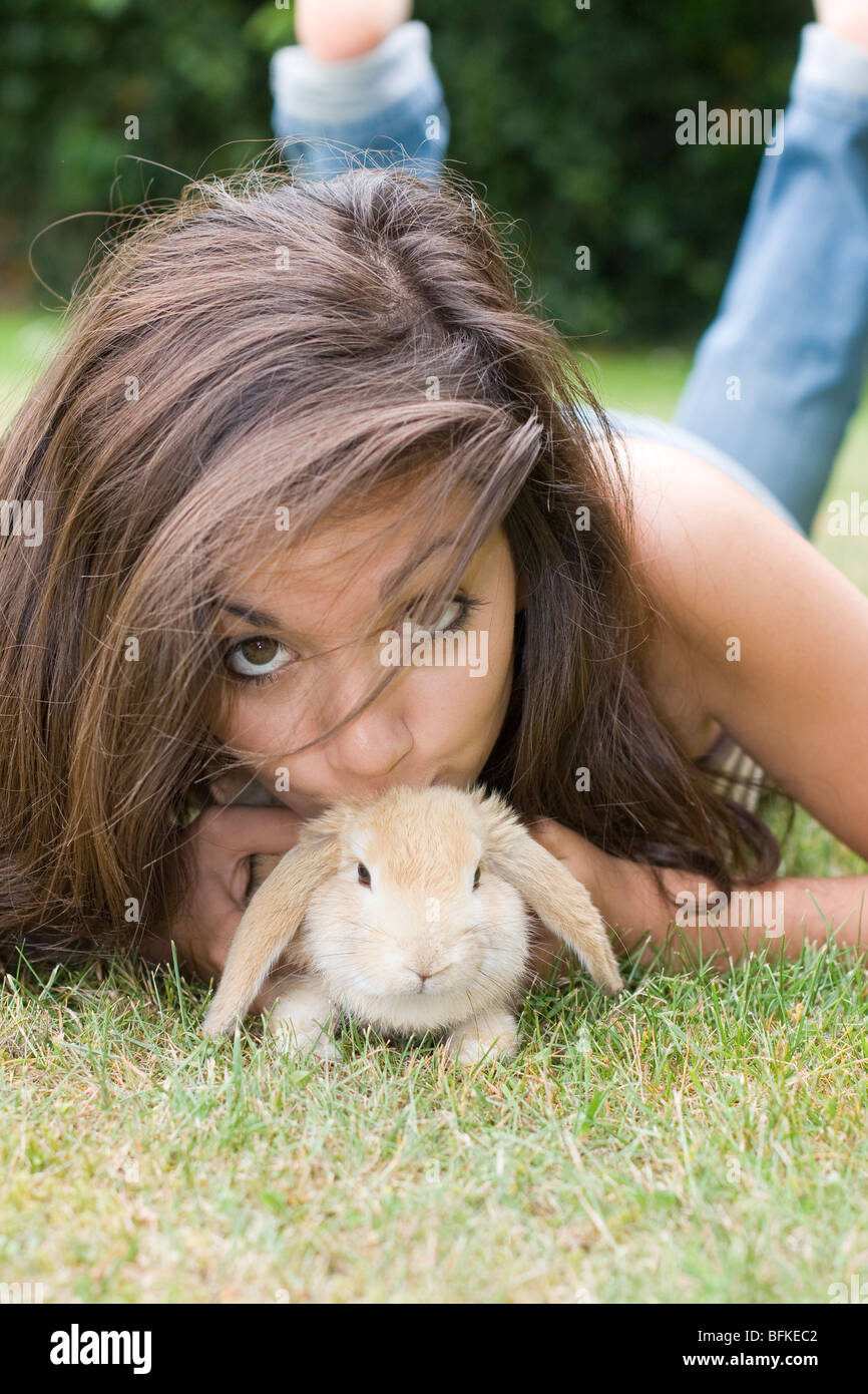 Ragazza adolescente sdraiati sull'erba con Pet Baby Rabbit Foto Stock