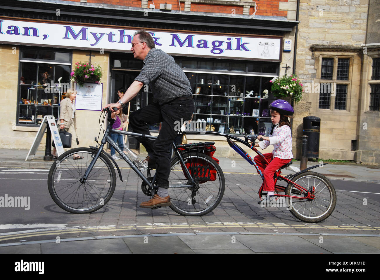 Padre e figlio in bicicletta al posto di mercato Glastonbury Somerset Inghilterra Foto Stock