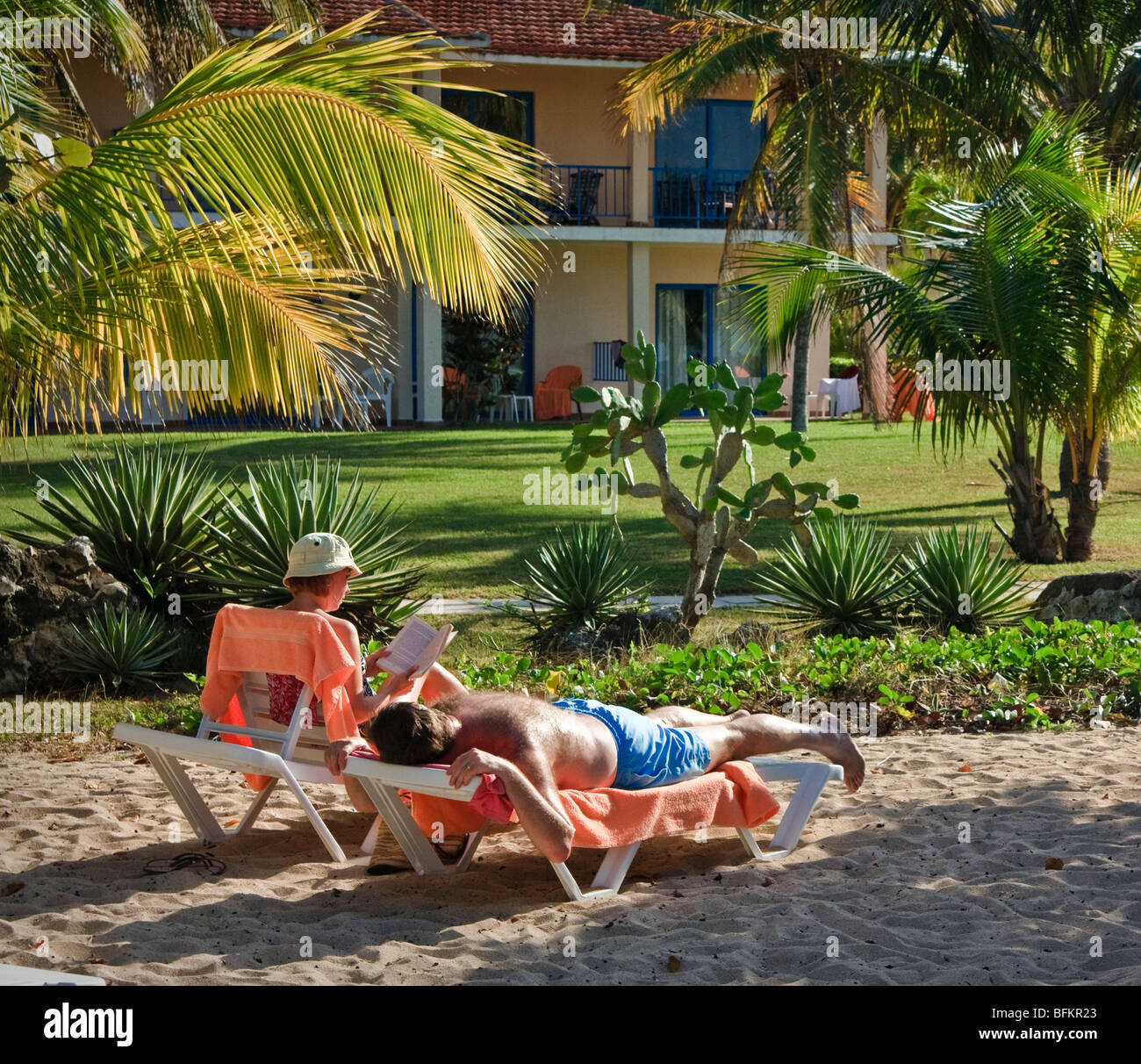 Un paio di relax presso il resort. La donna è la lettura di un libro, l'uomo che stabilisce la concia, resort caraibico Foto Stock