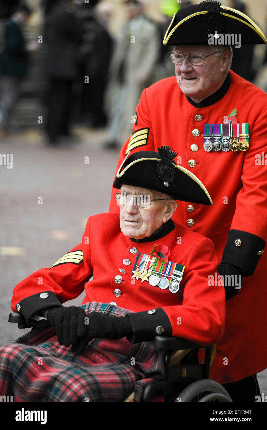 Un pensionato di Chelsea spingendo un disabili veterano di guerra in una sedia a rotelle. Foto Stock
