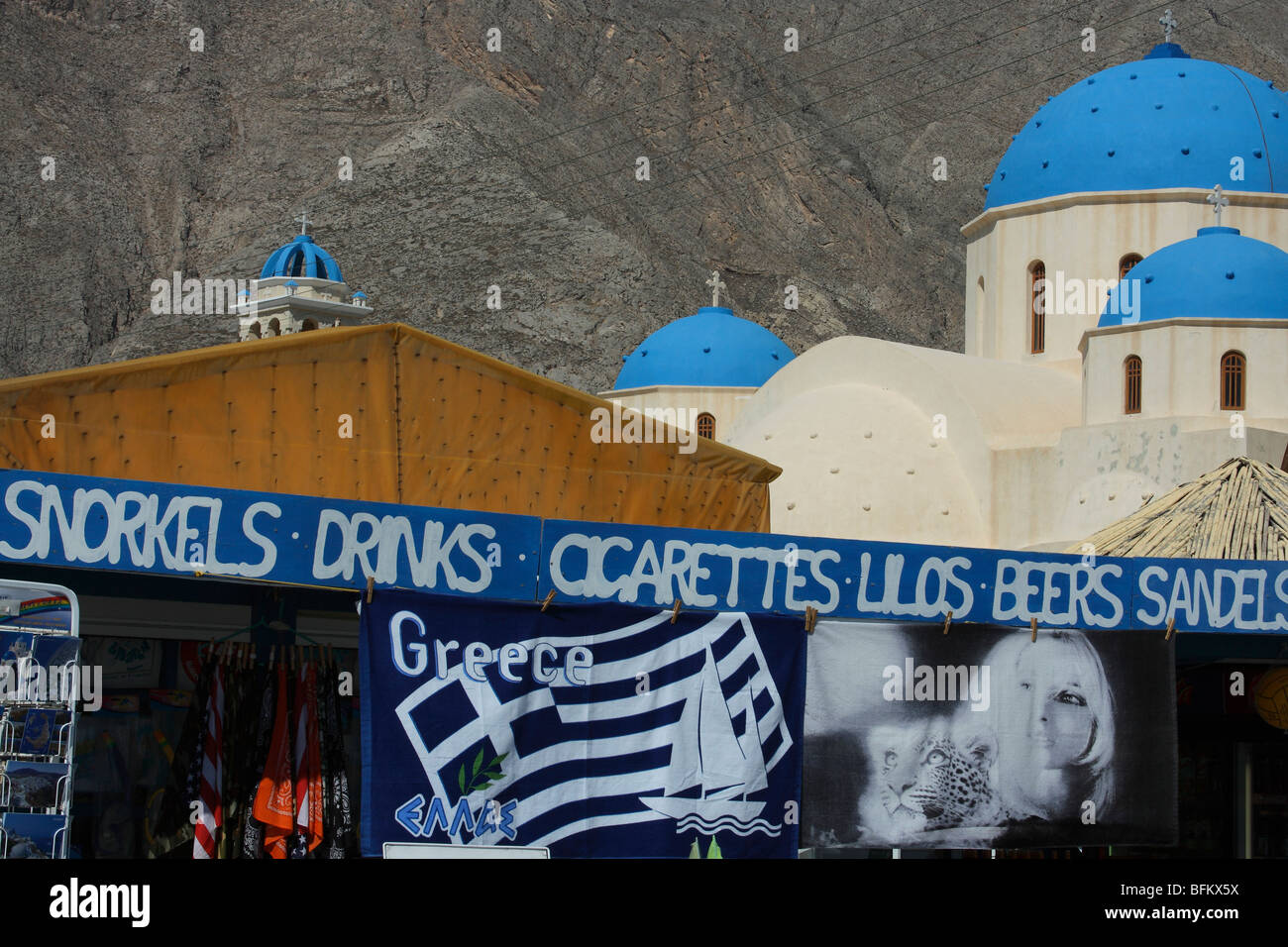 Negozio a Santorini beach resort con una bella chiesa con le cupole blu sullo sfondo Foto Stock