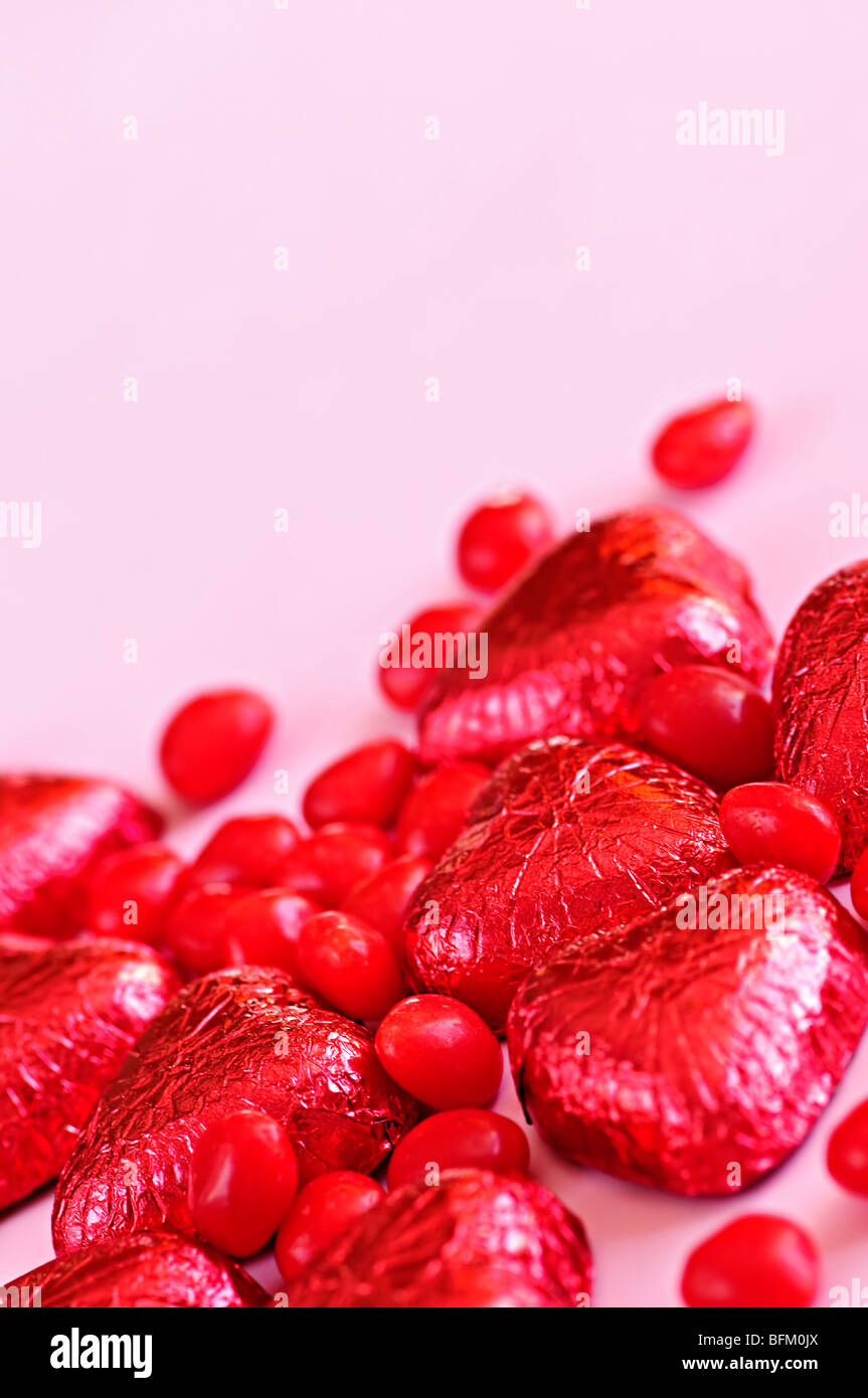 Rosso di San Valentino di caramelle e la lamina di cioccolatini incartati su sfondo rosa Foto Stock