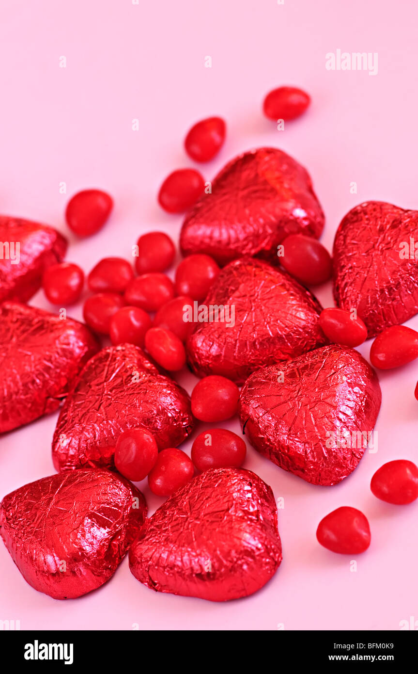 Rosso di San Valentino di caramelle e la lamina di cioccolatini incartati su sfondo rosa Foto Stock