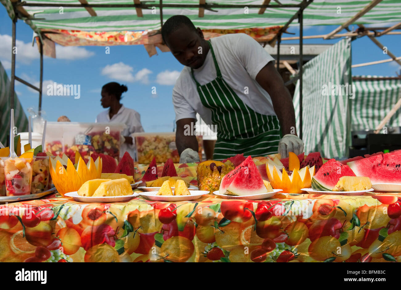 Uomo fresco di taglio i meloni e i cocomeri a evento all'aperto Foto Stock