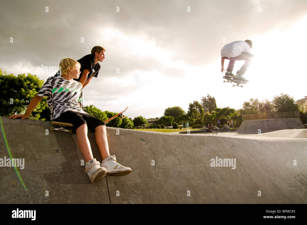 3 ragazzi facendo acrobazie in skate park con regolazione del sole, Cambridge, Nuova Zelanda, Foto Stock