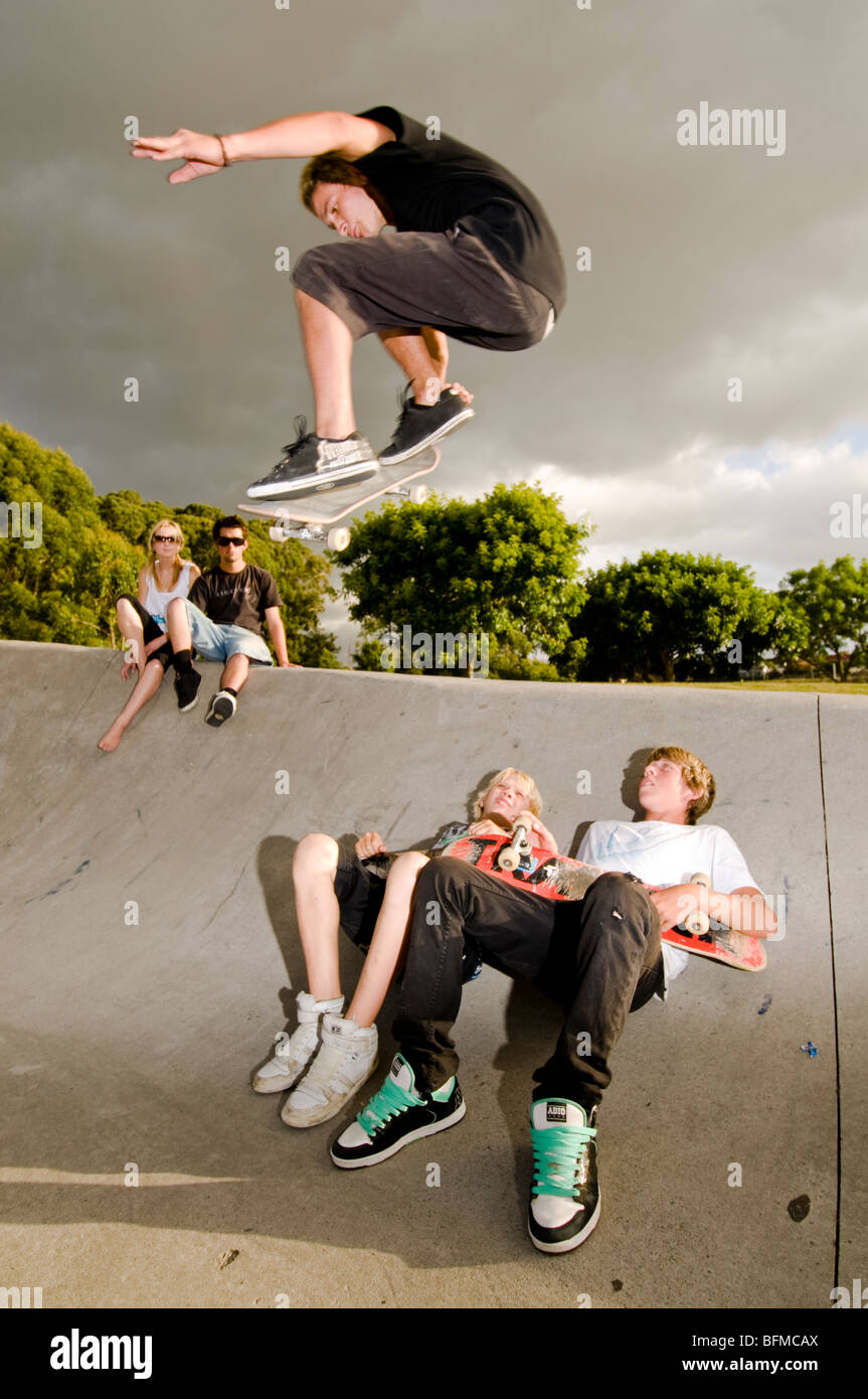 3 ragazzi facendo acrobazie in skate park con regolazione del sole, Cambridge, Nuova Zelanda, Foto Stock