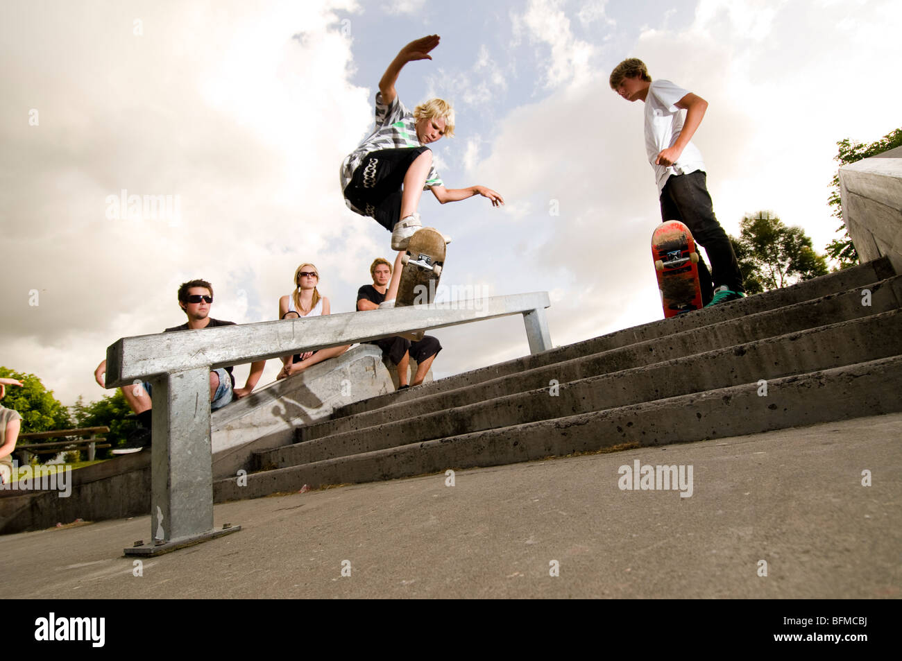 3 ragazzi facendo acrobazie in skate park con regolazione del sole, Cambridge, Nuova Zelanda, Foto Stock