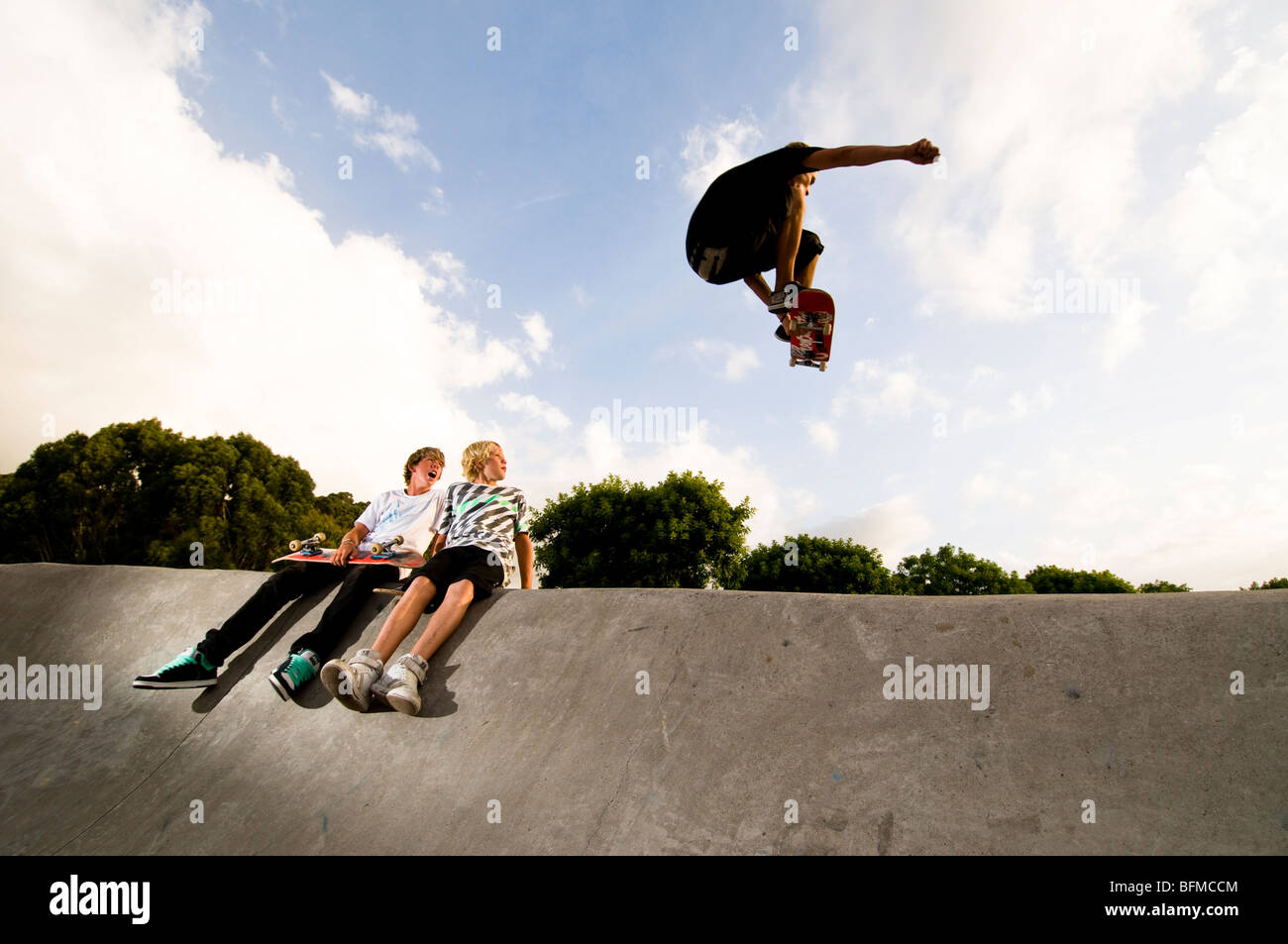 3 ragazzi facendo acrobazie in skate park con regolazione del sole, Cambridge, Nuova Zelanda, Foto Stock