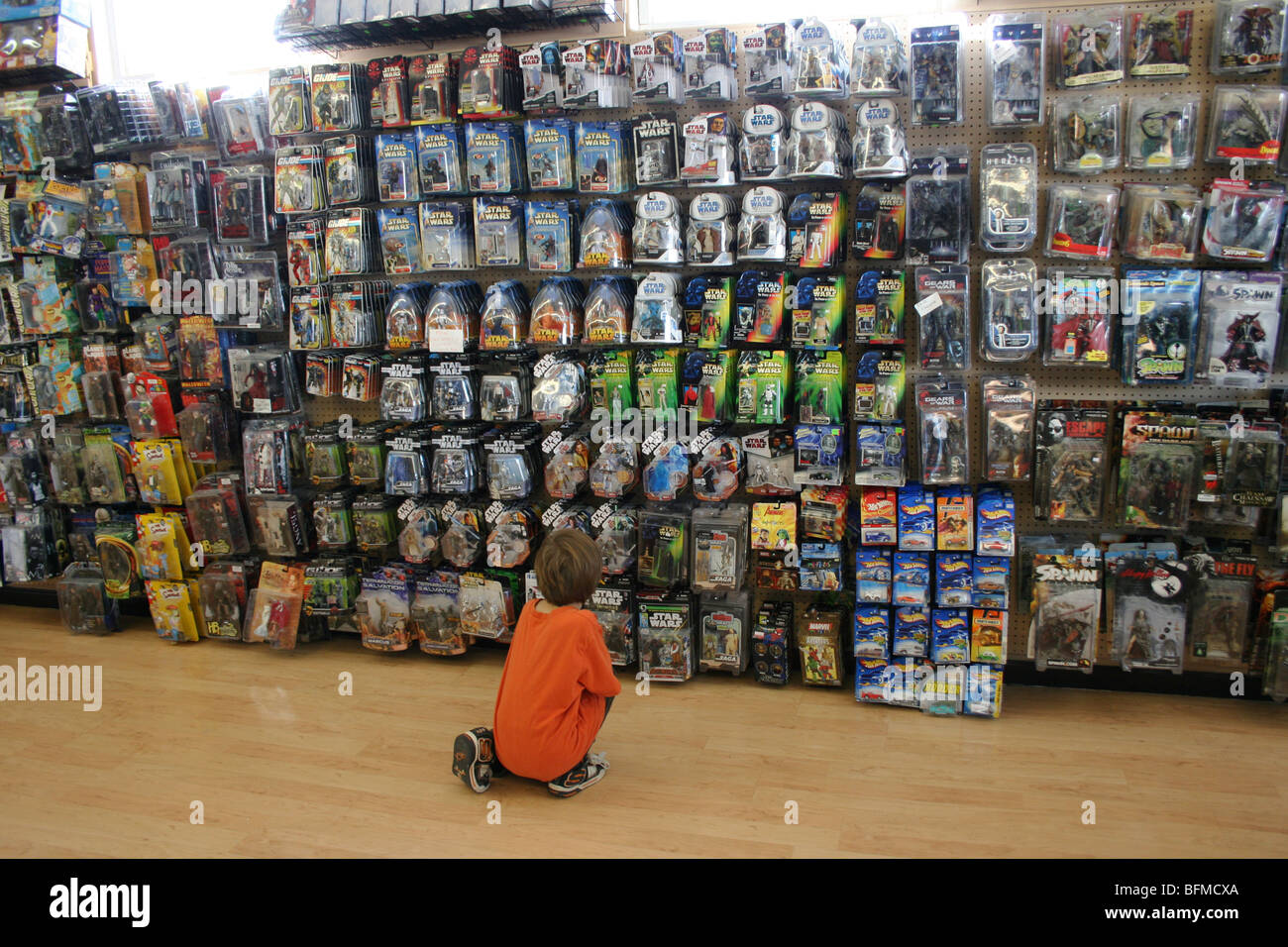 Bambino guardando azione assortiti figura giocattoli in un negozio di giocattoli, southwestern usa Foto Stock