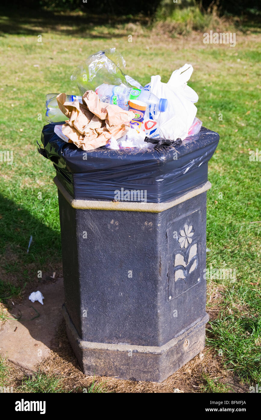 Un bidone della spazzatura in un parco pubblico traboccante di spazzatura in generale e dei contenitori di plastica. Il Dorset. In Inghilterra. Regno Unito. Foto Stock