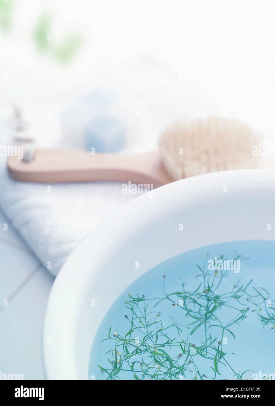 Ciotola con erbe aromatiche e prodotti di cortesia da bagno su asciugamano Foto Stock