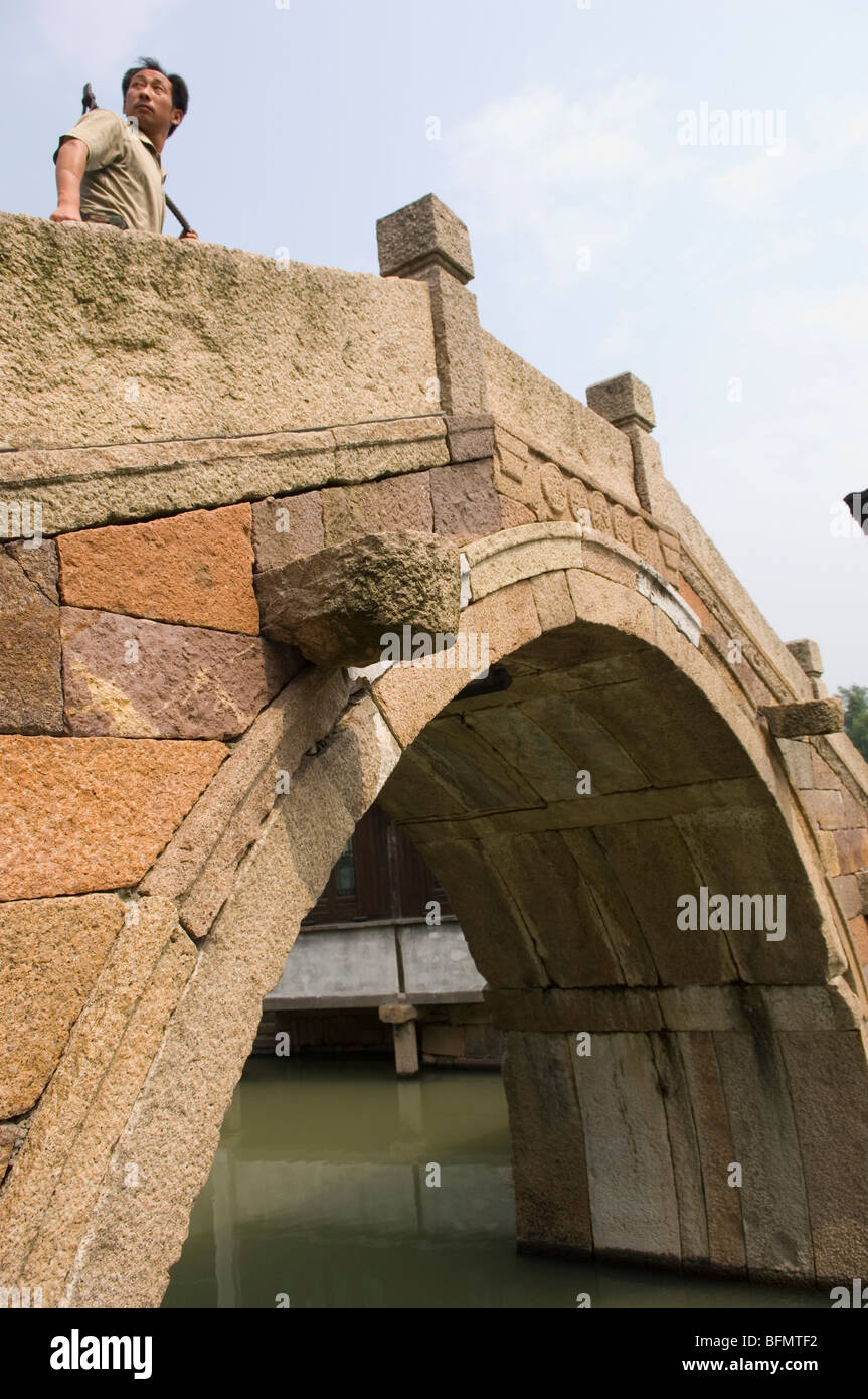 L'uomo attraversando un ponte arcuato nella città d'acqua Wuzhen. La provincia di Zhejiang, Cina. Foto Stock