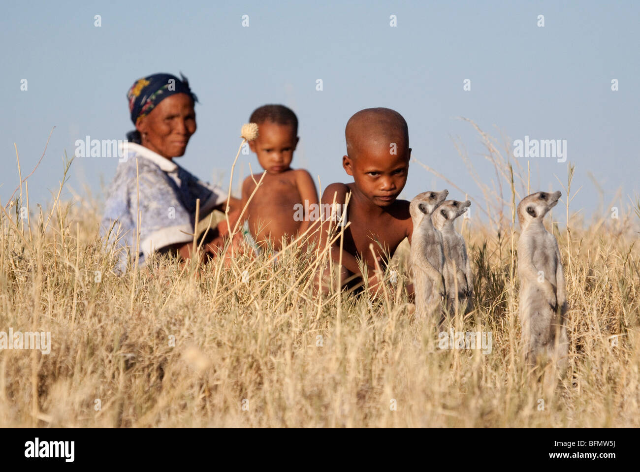 Il Botswana, Makgadikgadi. I Boscimani giocare i bambini in erbe secche del Kalahari, guardati da loro madre. Foto Stock