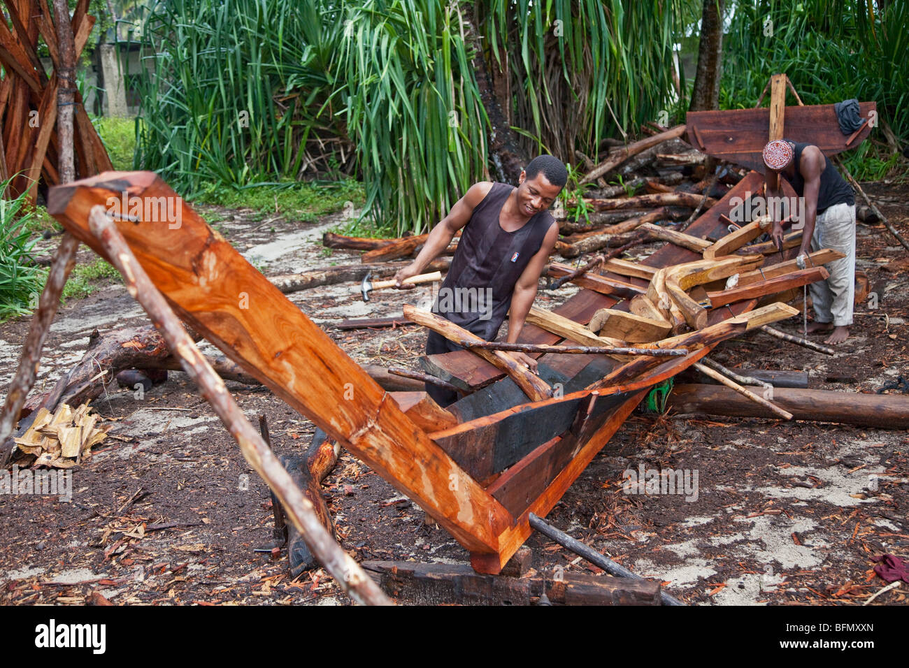 Tanzania, Zanzibar. Gli artigiani costruire un DAC, un di legno barca a vela comunemente chiamato un dhow, sulla spiaggia di Nungwi. Foto Stock