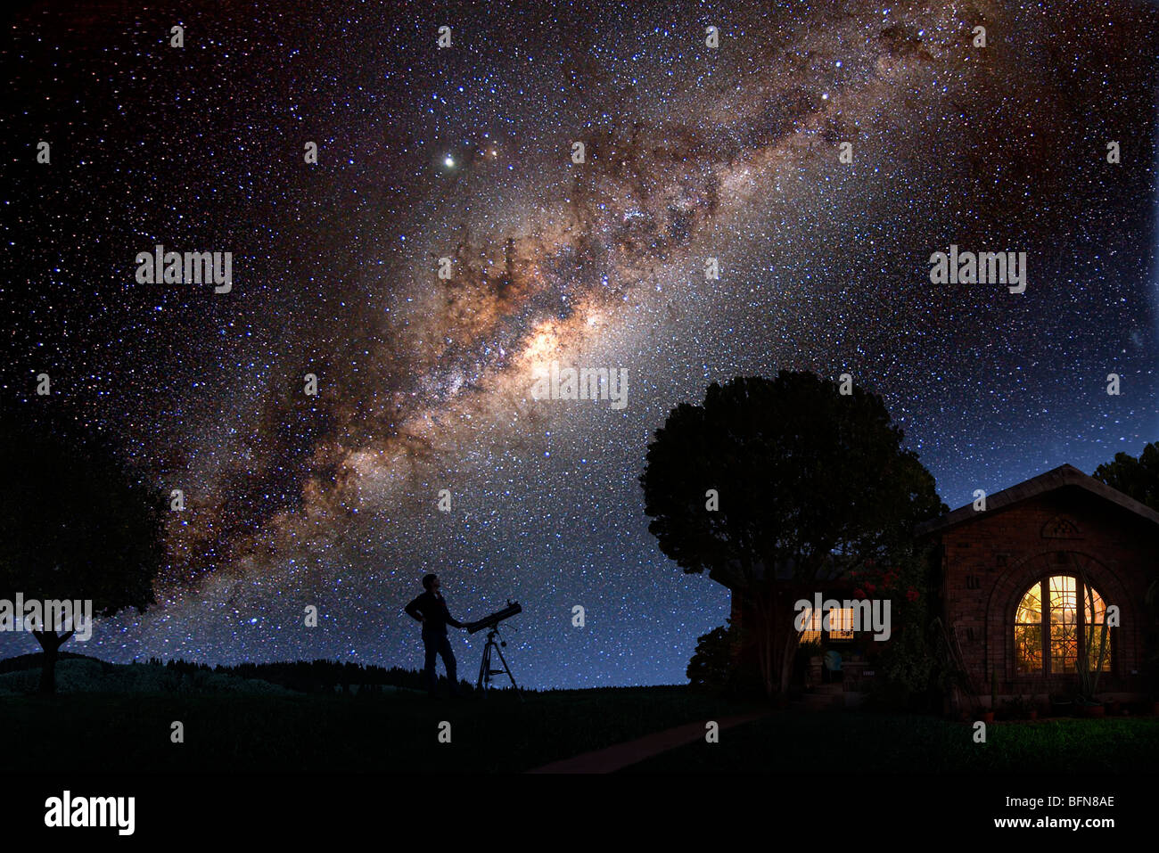 Un uomo guarda la Via Lattea al di fuori della sua casa a notte Foto Stock