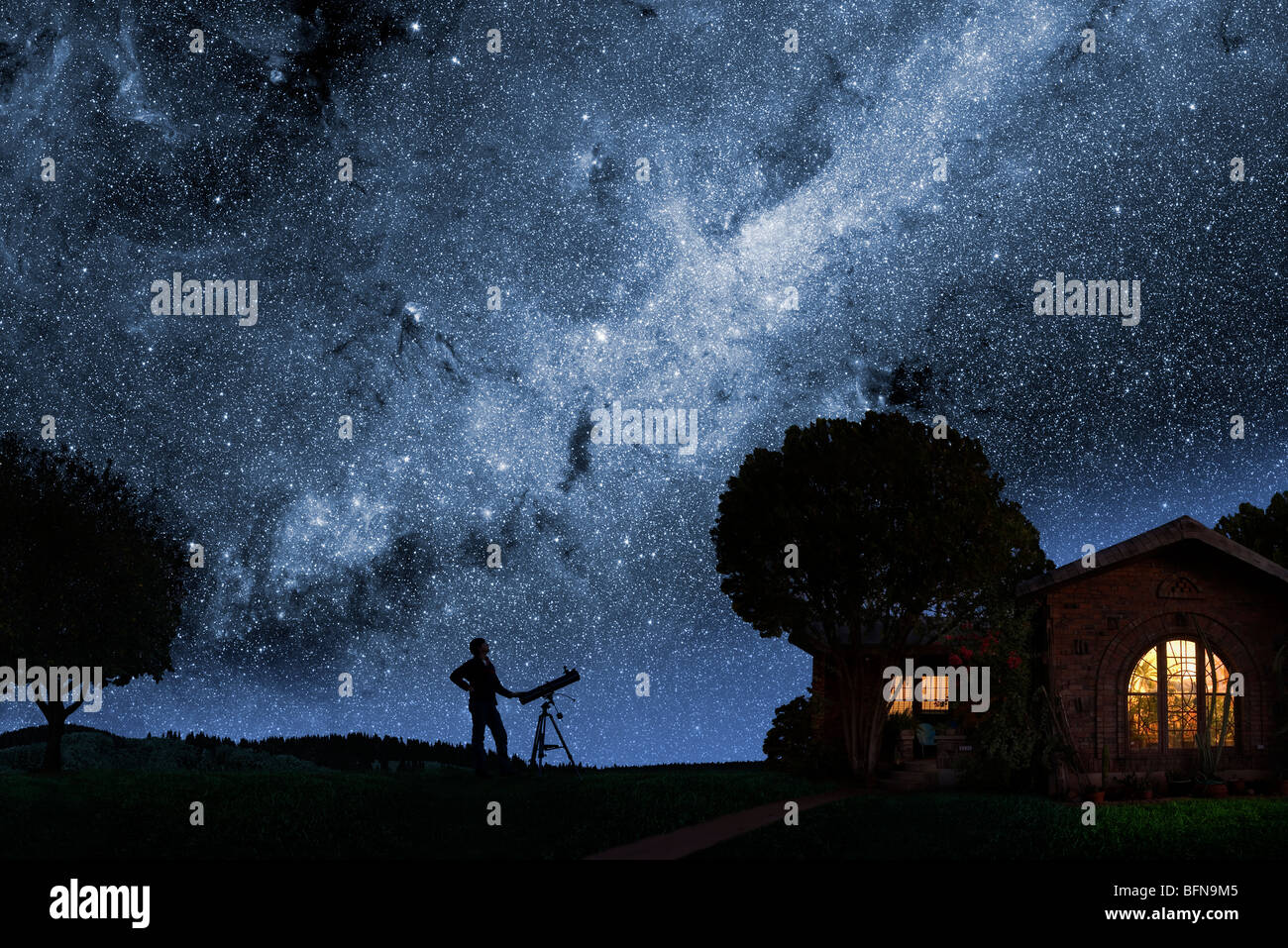 Un uomo guarda la Via Lattea al di fuori della sua casa a notte Foto Stock