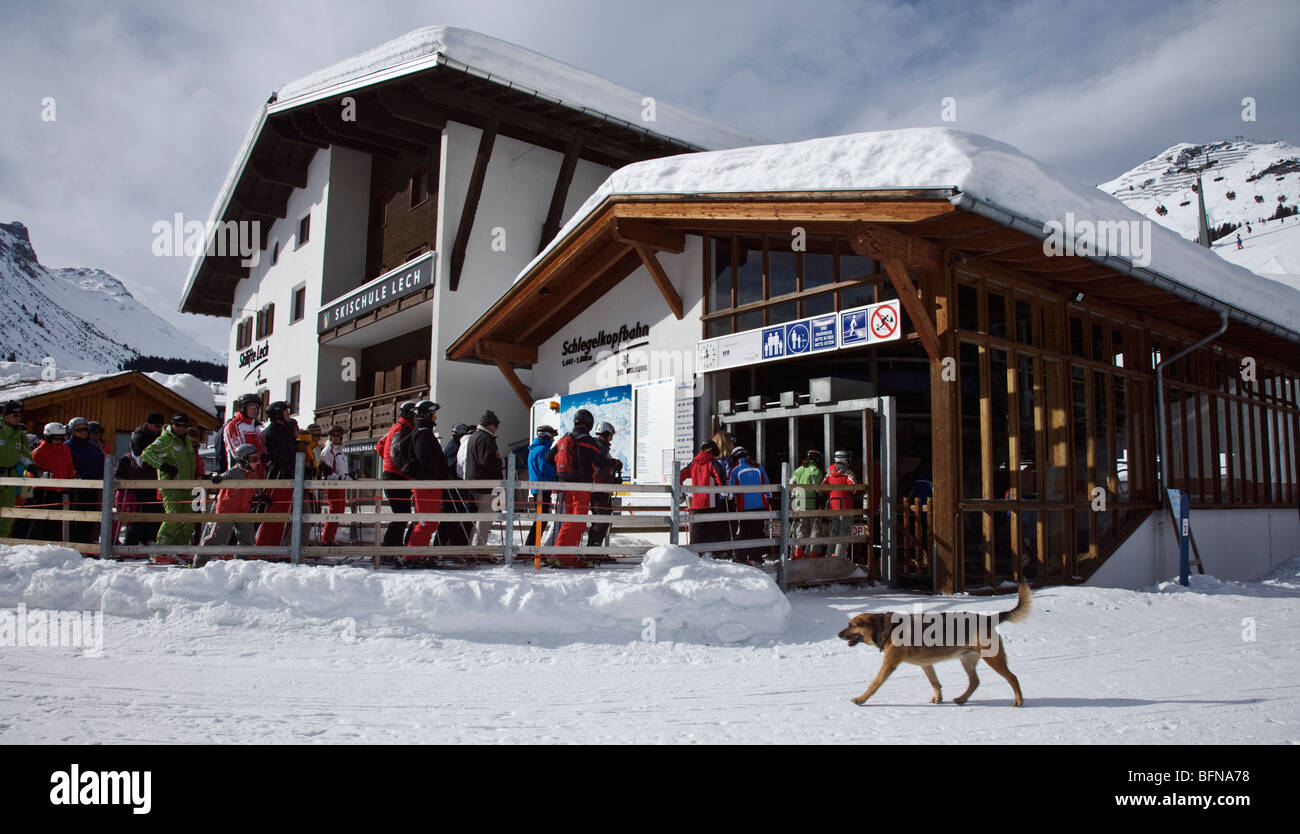 Gli sciatori in attesa di ottenere sulla seggiovia in Austrian Ski resort di Lech - un cane è passato a piedi in primo piano ignorarli Foto Stock