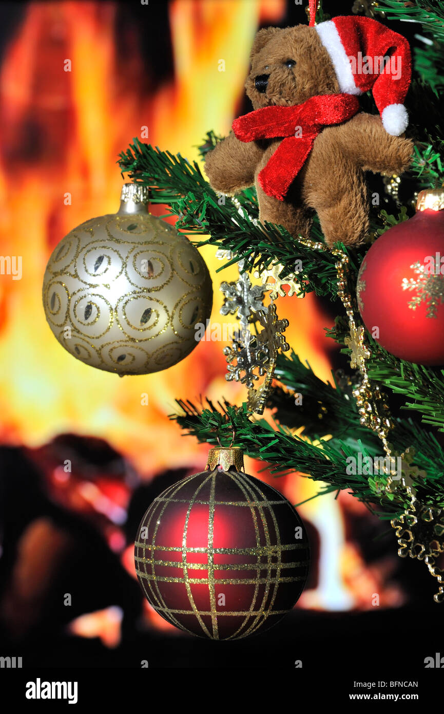 Orsacchiotto di peluche e campanelle in albero di Natale nella parte anteriore del focolare / camino Foto Stock