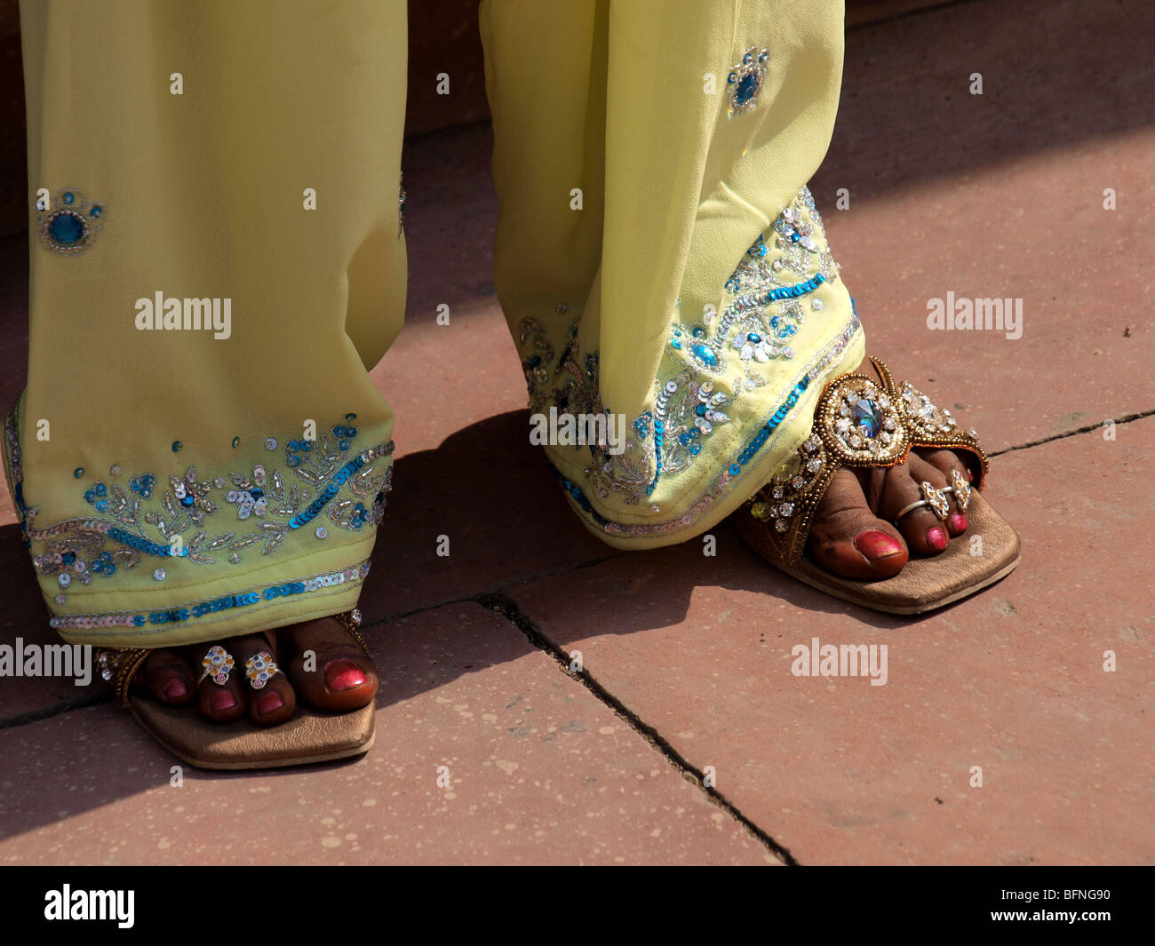 Decorate bejewelled piedi della signora indiana con orli sequined di giallo pallido pantaloni Foto Stock