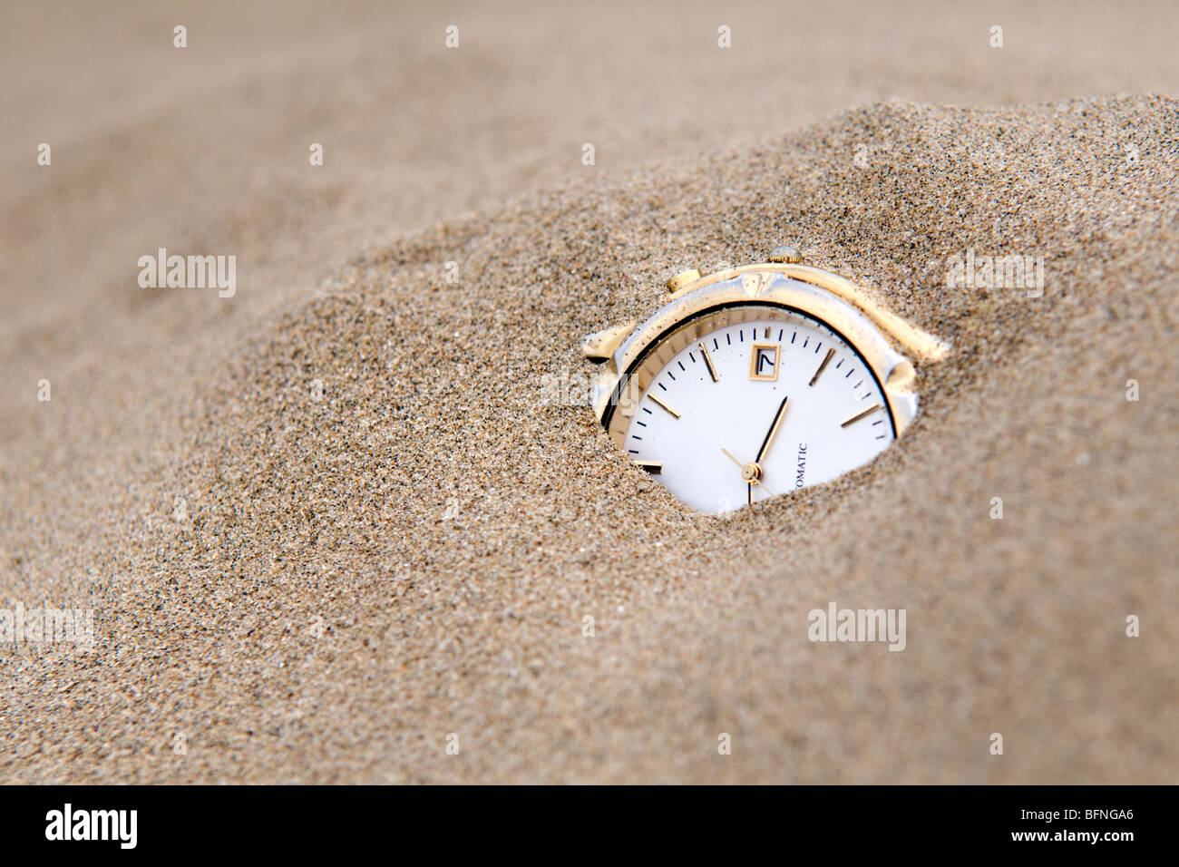 Orologio sepolto in sabbia presi per raffigurare le sabbie del concetto di tempo Foto Stock