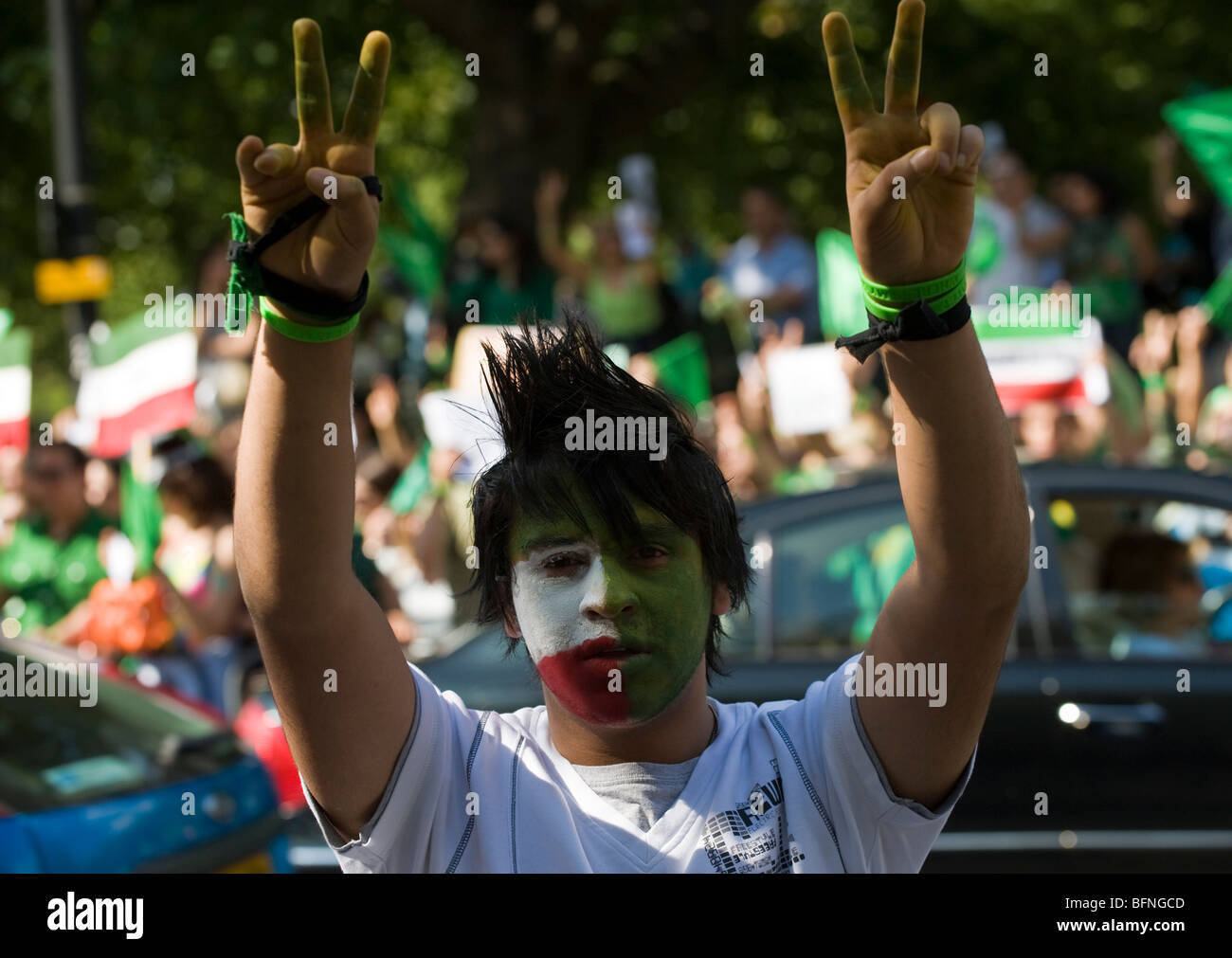 Giovane uomo con il suo volto dipinto con i colori della bandiera iraniana a protestare al di fuori dell'ambasciata iraniana, Londra Foto Stock