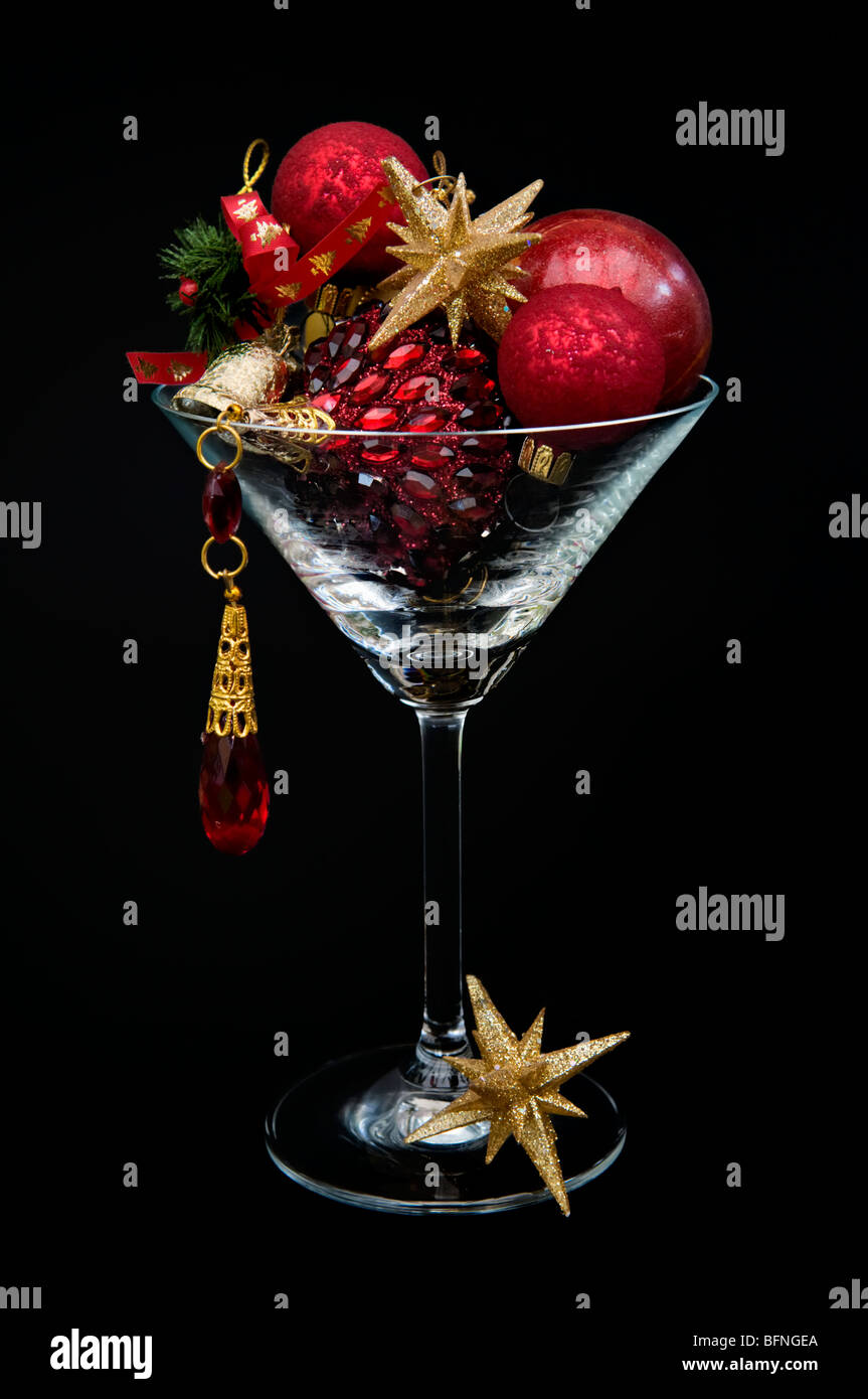 Rosso e oro decorazioni di Natale nel bicchiere da cocktail contro uno sfondo nero Foto Stock