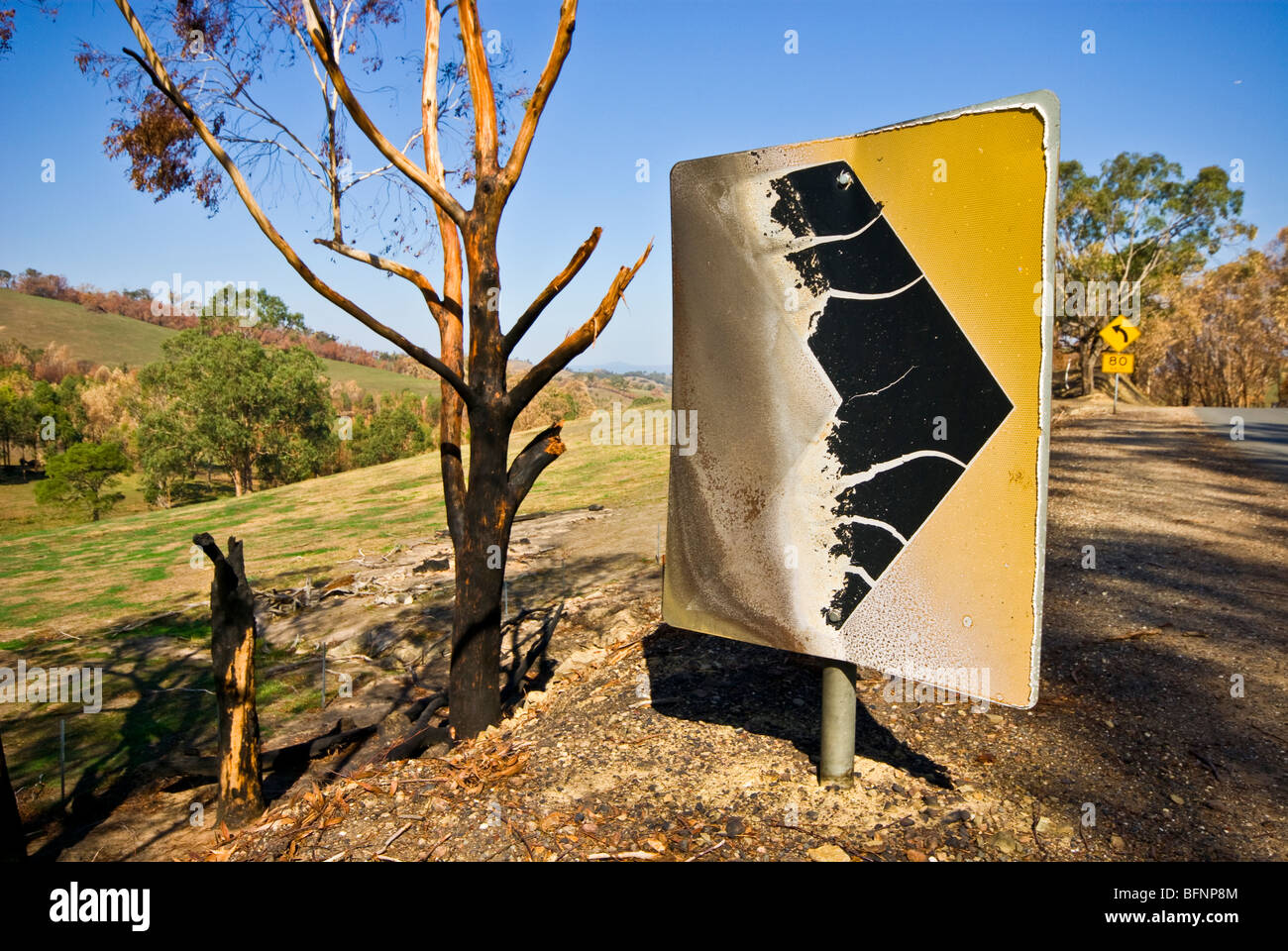 Un incendio di metallo danneggiato il simbolo di sicurezza su una curva in una strada di campagna. Foto Stock
