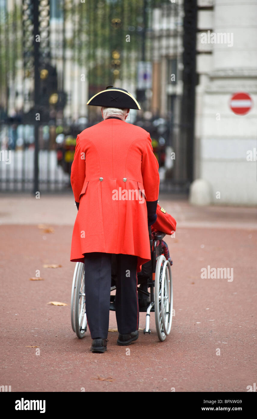 Un pensionato di Chelsea spingendo un disabili veterano di guerra in una sedia a rotelle. Foto Stock