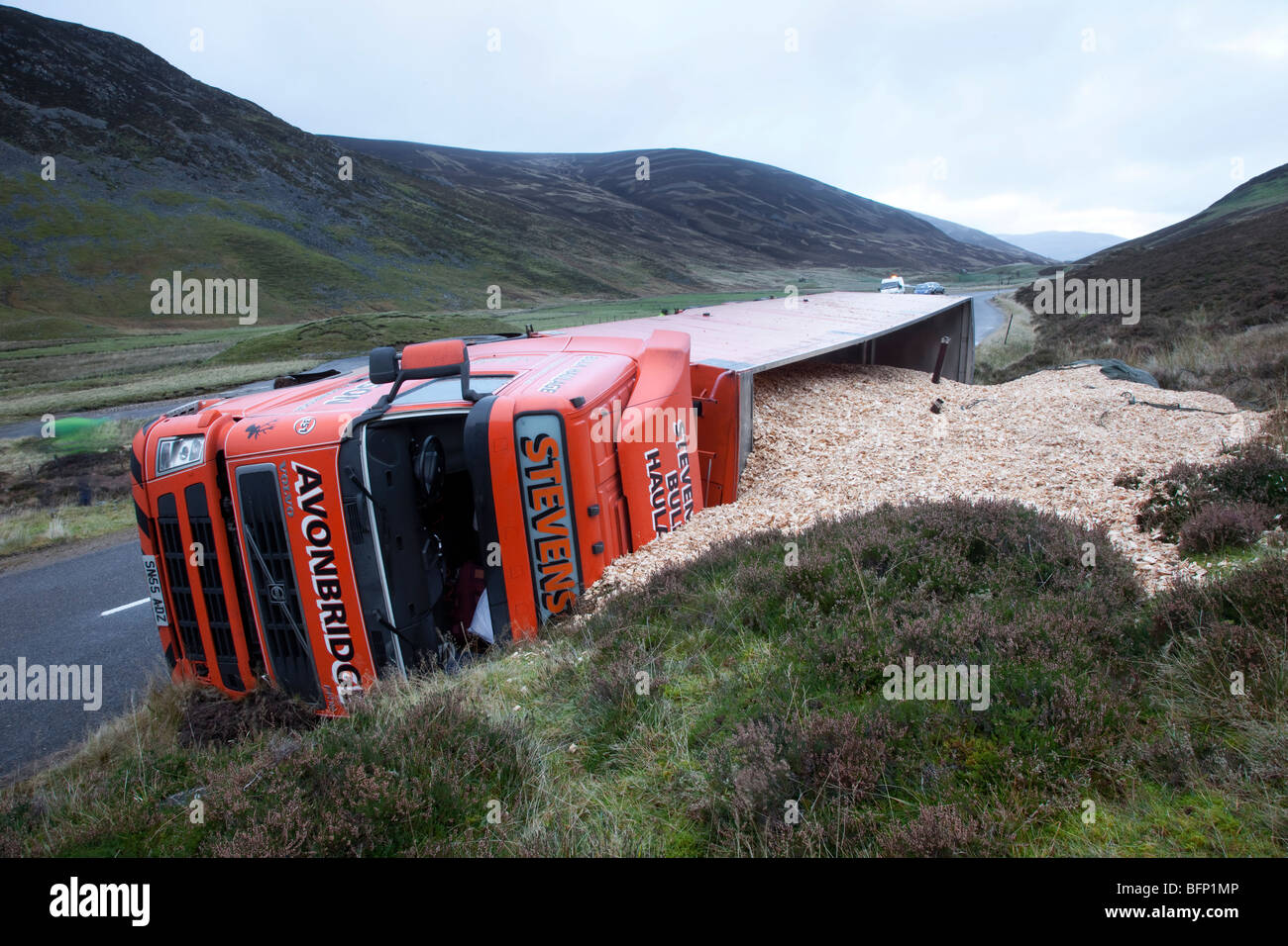 Capovolto merci pesanti camion di legno che spillano legno segheria rifiuti di legno sfuso trucioli di legno. Incidente stradale sulla A93 Braemar per Glenshee Road, Scozia, Regno Unito Foto Stock