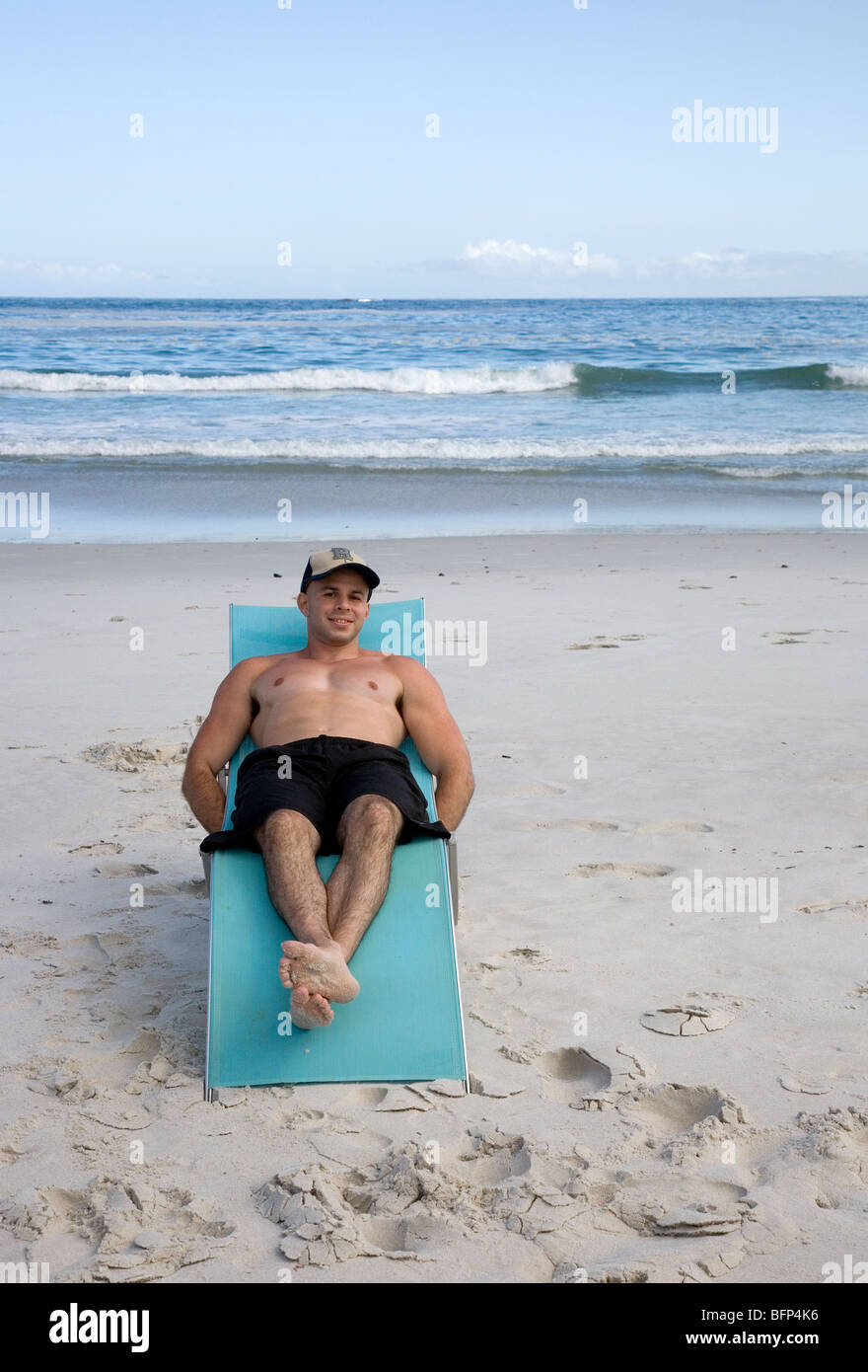 L'uomo con il cappello sulla spiaggia sdraio Foto stock - Alamy