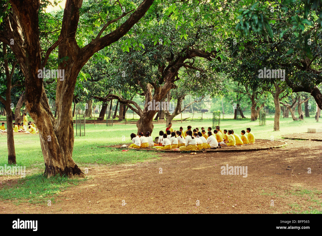 Insegnante e studenti che studiano sotto albero di mango boschetto, Shanti Niketan, Shantiniketan, Bolpur, Birbhum, Bengala Occidentale, India, Asia Foto Stock