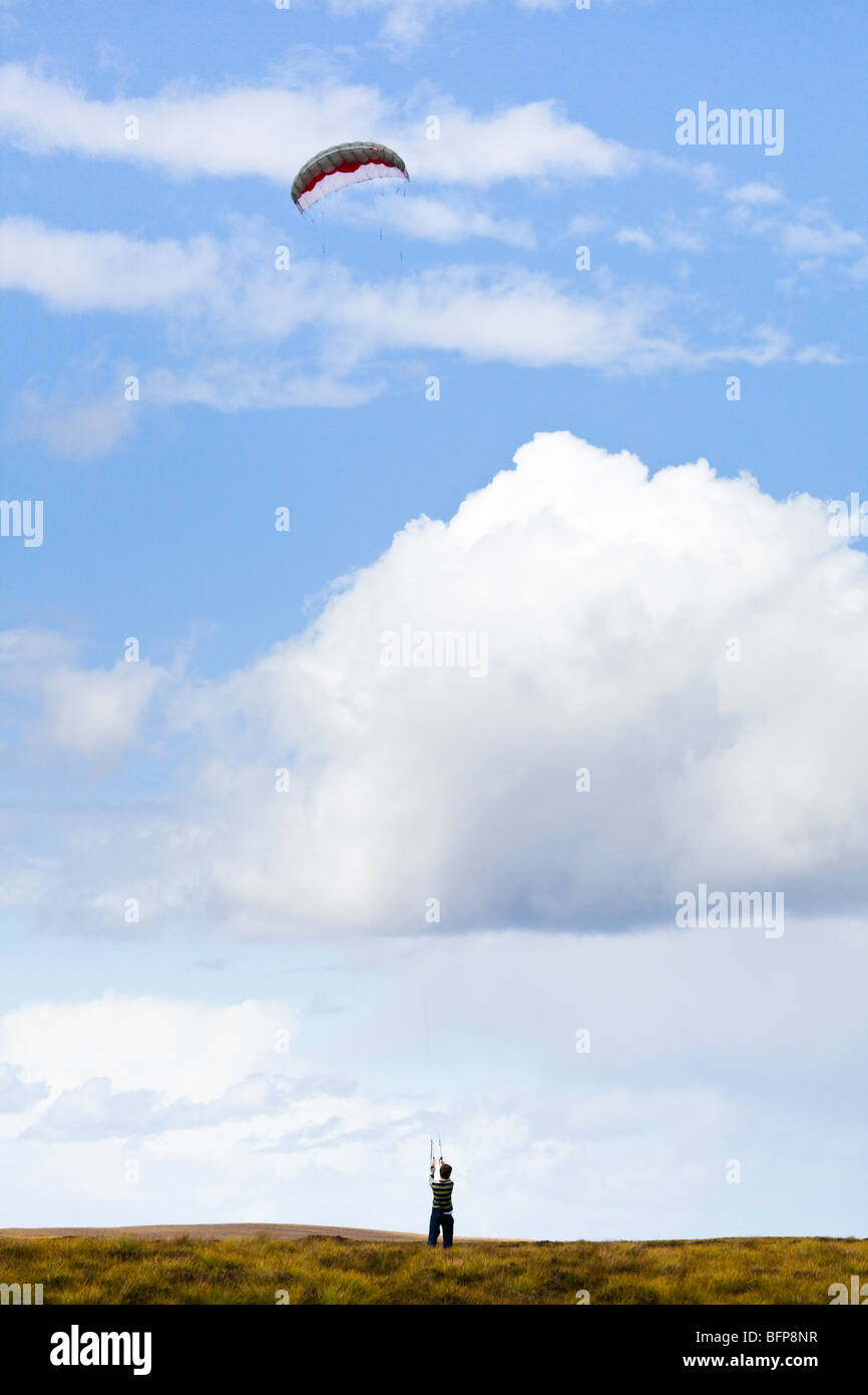 Un giovane uomo di volare un aquilone di potenza in condizioni di vento forte sulla brughiera est di Syre, Sutherland, Highland, Scozia Foto Stock