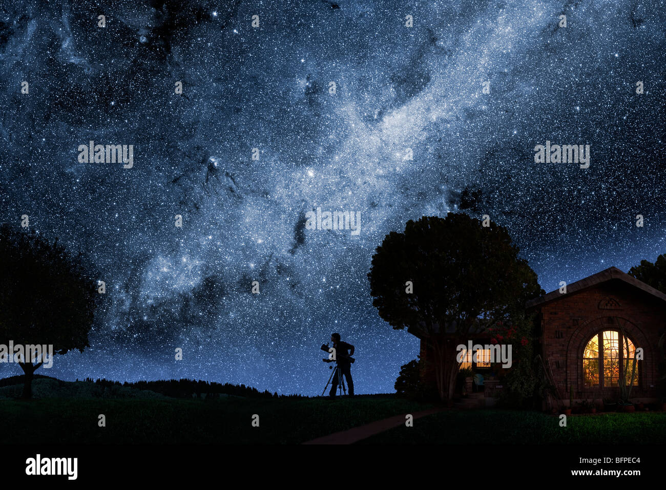 Un uomo guarda la Via Lattea al di fuori della sua casa a notte Foto Stock