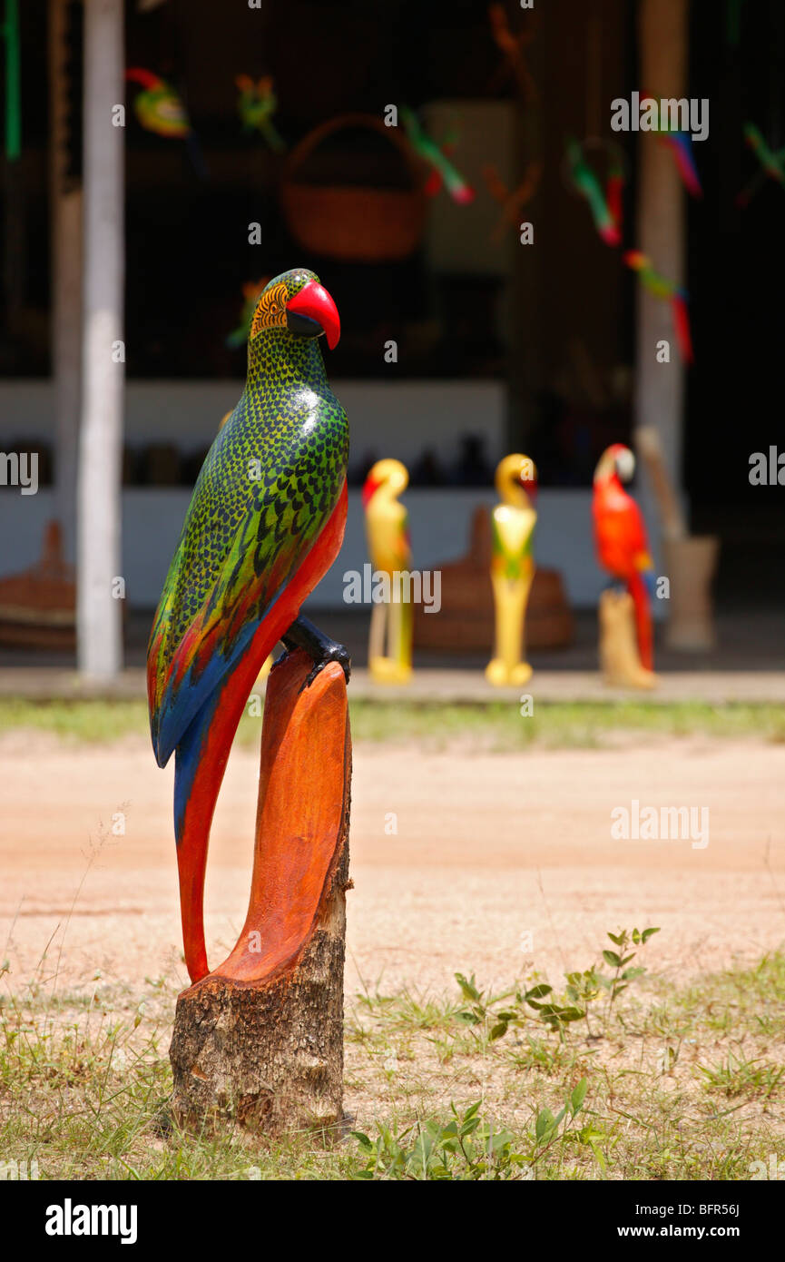 Una curiosità sul ciglio della strada in stallo con un grande in legno intagliato parrot Foto Stock