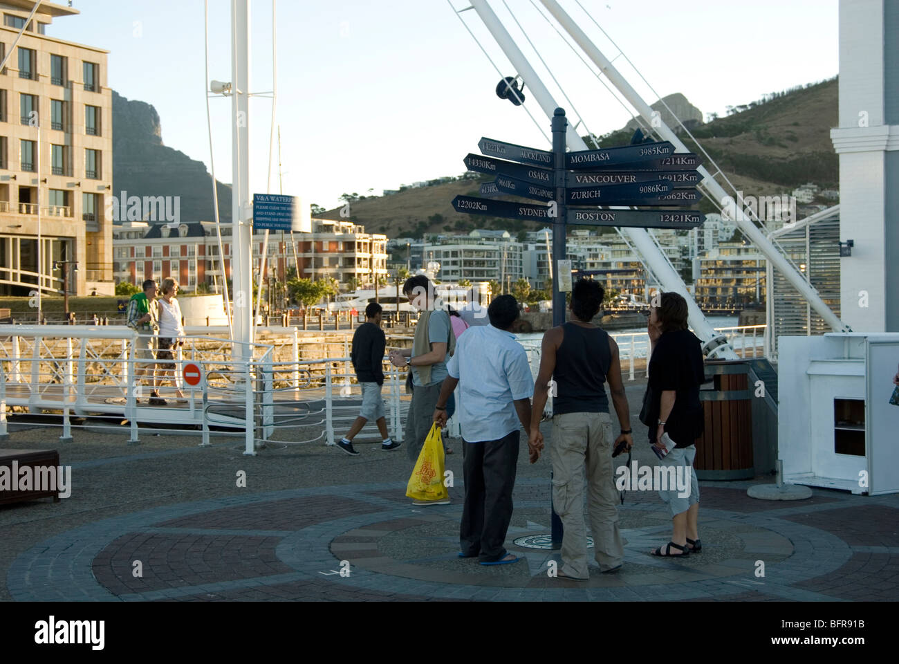 I turisti che cercano a distanza di marcatori per le città di tutto il mondo al Victoria and Alfred Waterfront Foto Stock