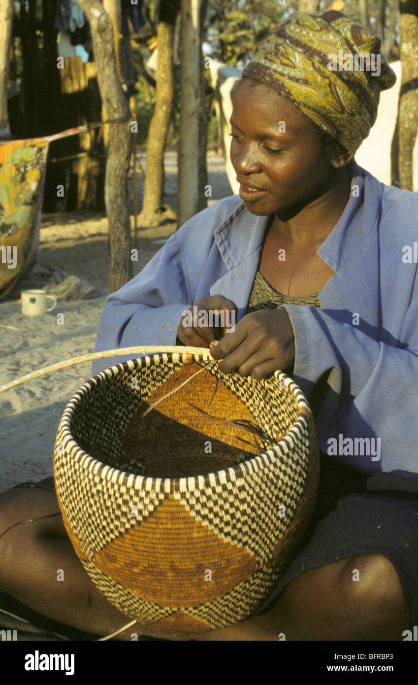 Donna Bayei tessitura di un cestello con strisce di foglie di palmo tinti con colori prodotti da estratti vegetali. Foto Stock