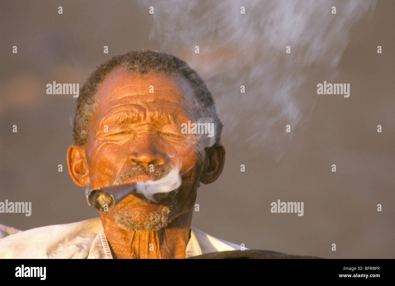 Un uomo San da Ghanzi fumare una tubazione tradizionale Foto Stock