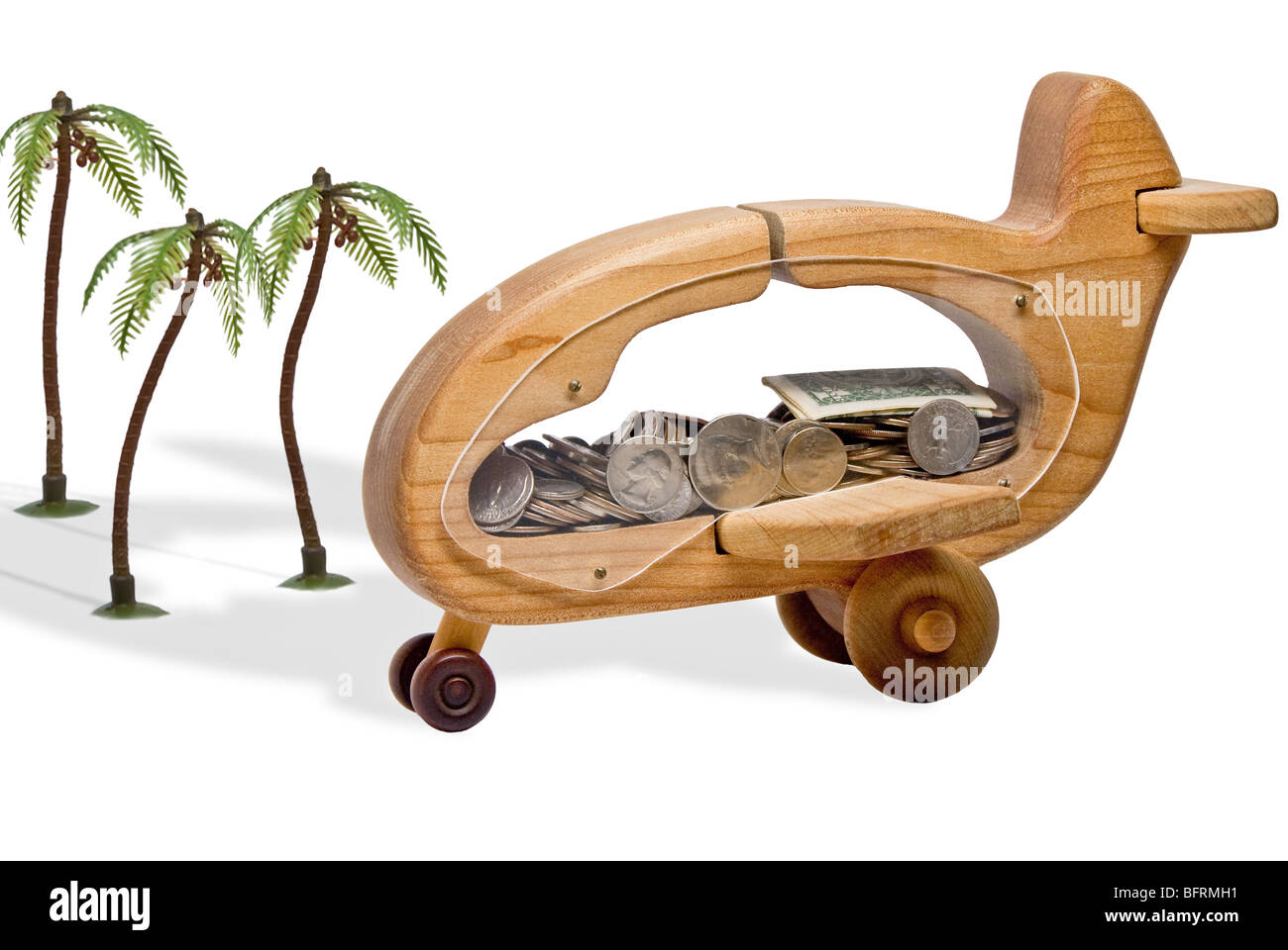 Aeroplano di legno pieno di soldi in posizione tropicale, studio shot Foto Stock