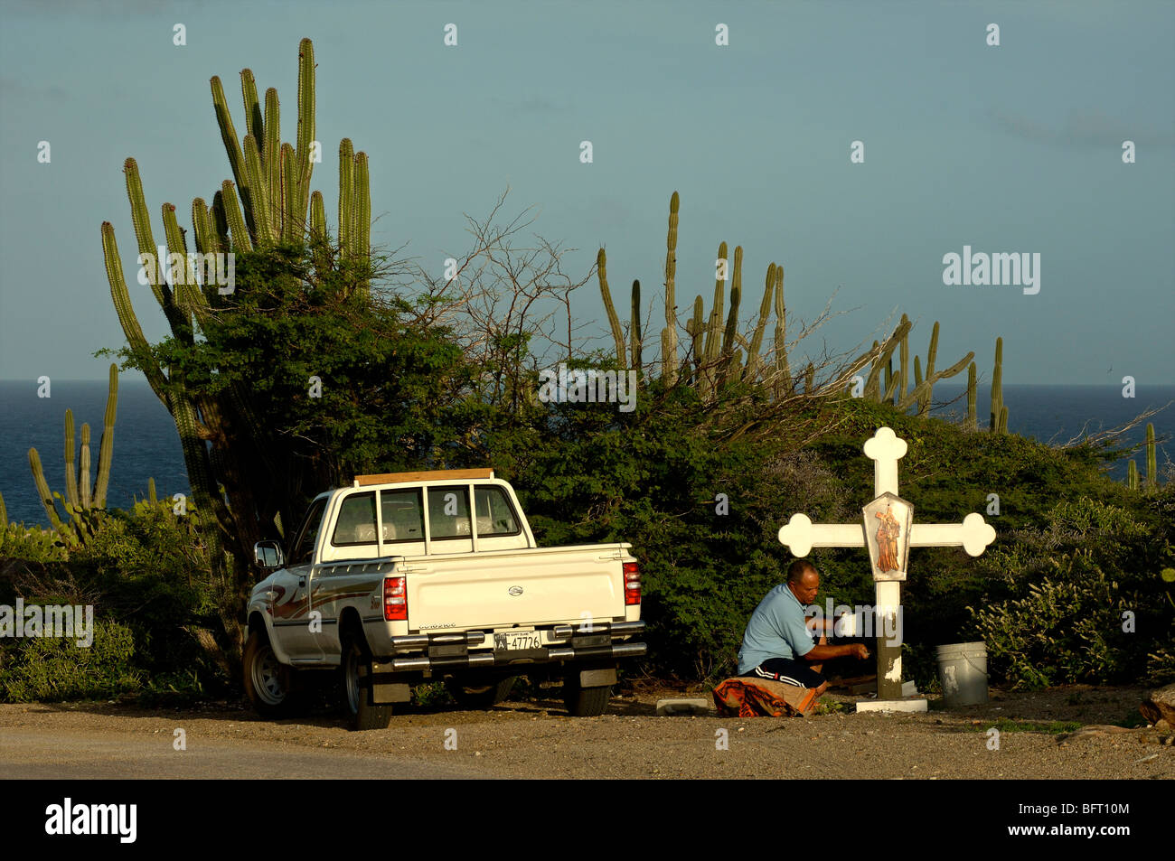Aruba, uomo pittura una croce accanto alla strada Foto Stock