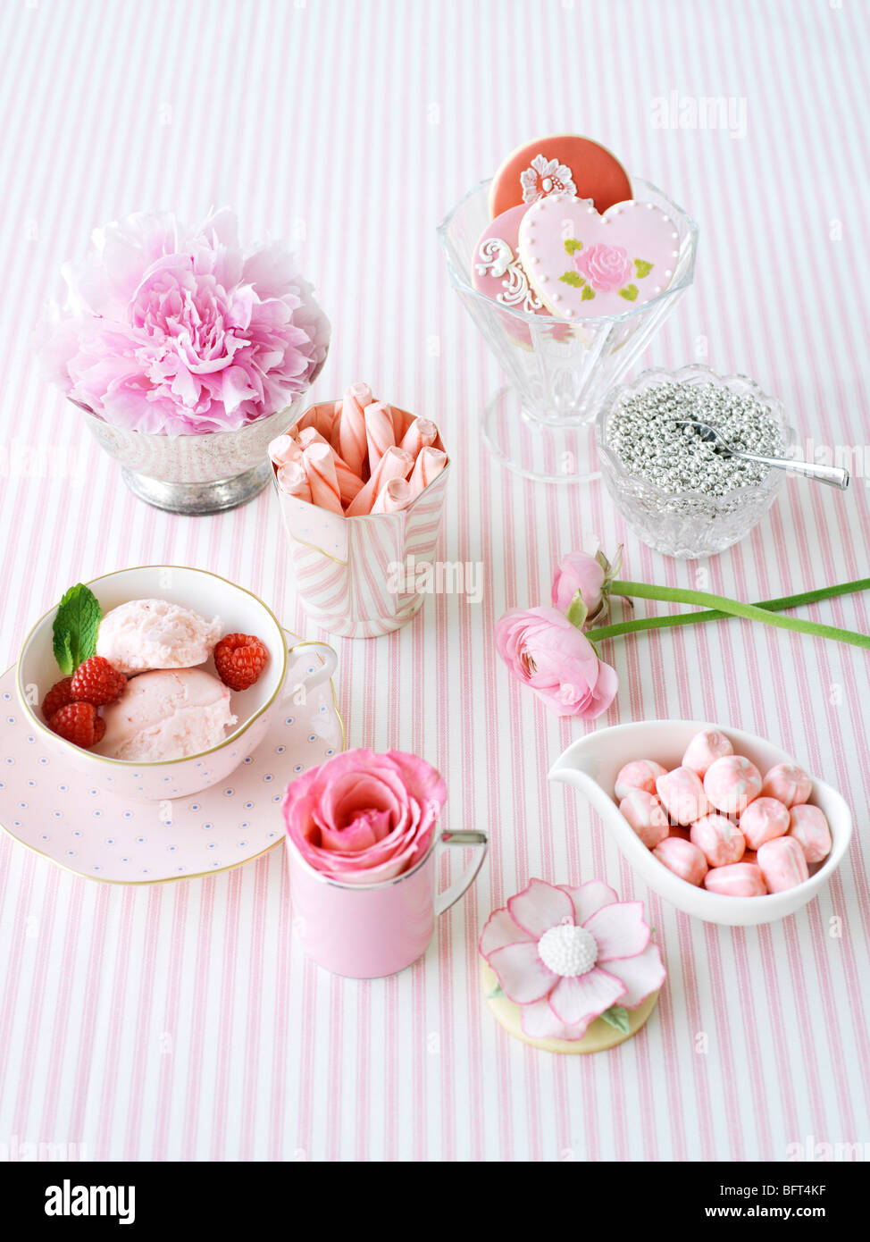 Tazze da tè e piatti pieni di dolci e fiori Foto Stock
