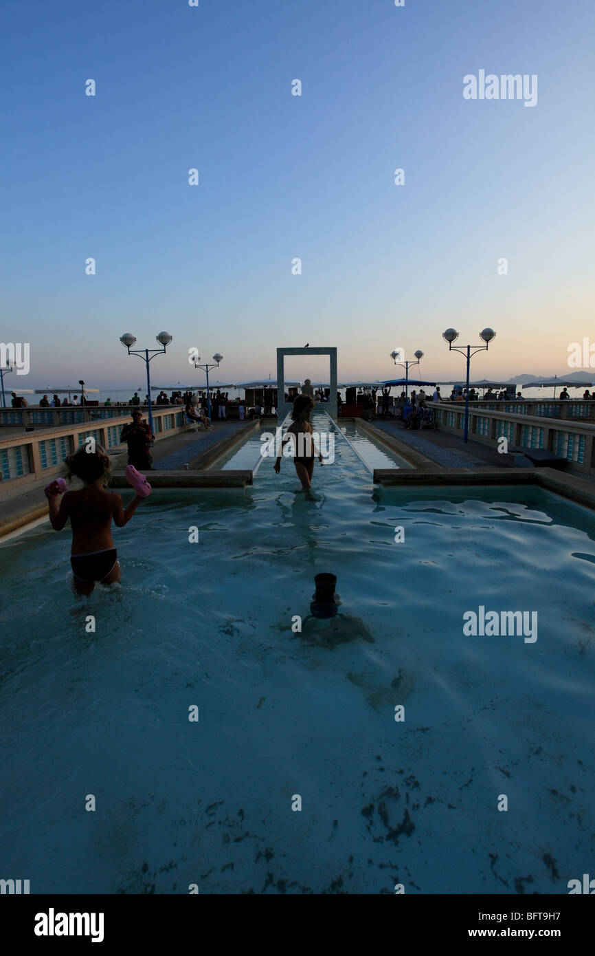 Il Mediterraneo città costiera di Juan les Pins e la fontana con la vasta bassin affacciate sul mare di notte. Foto Stock