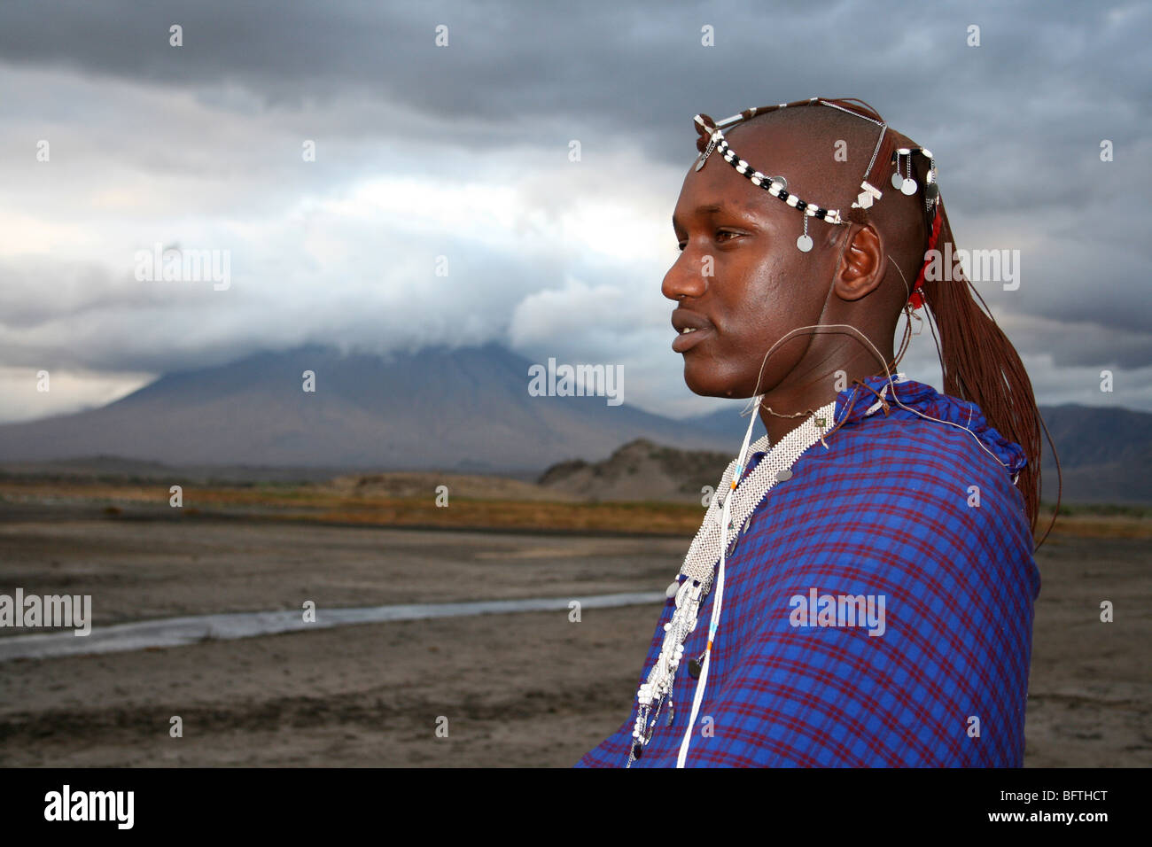 Guerriero Masai sorge accanto a Ol Doinyo Lengai in Tanzania Foto Stock