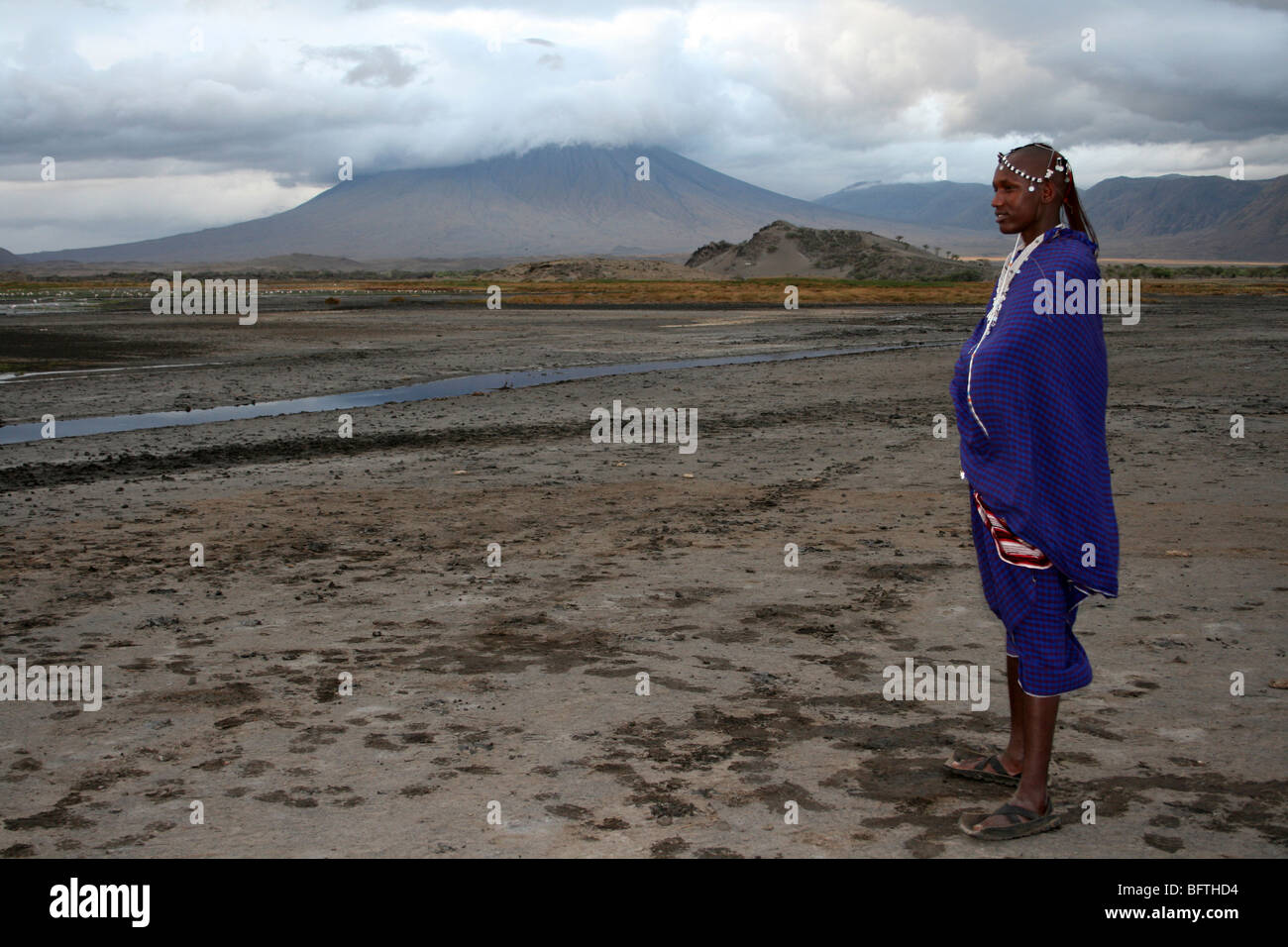 Guerriero Masai sorge accanto a Ol Doinyo Lengai in Tanzania Foto Stock