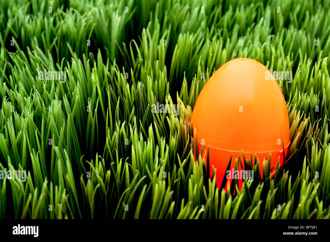 L'immagine orizzontale di un arancio uovo di Pasqua su erba verde Foto Stock
