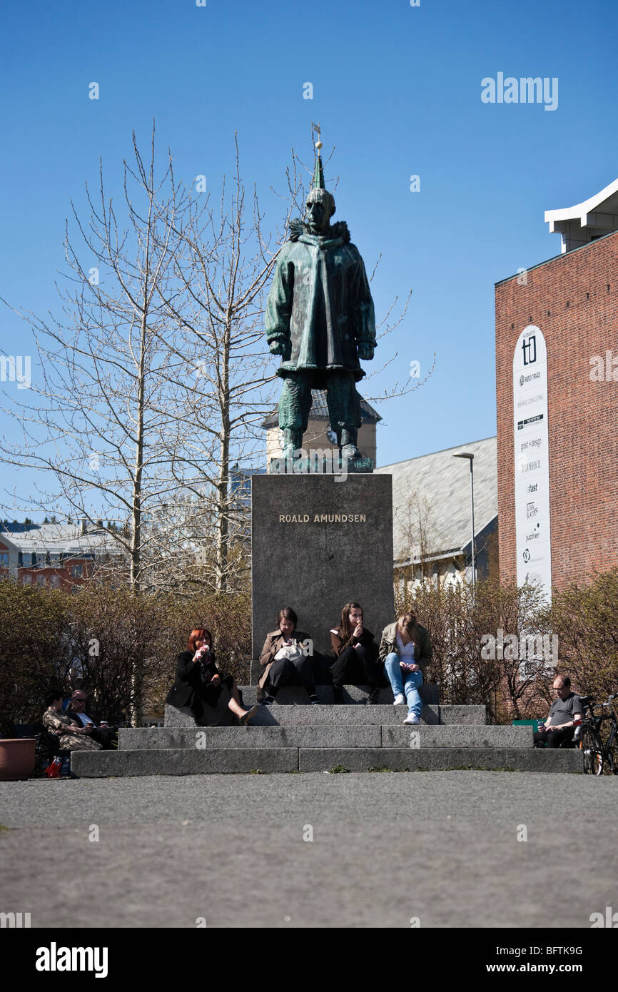 Statua di Roald Amundsen in Tromso Norvegia, adolescenti seduta sulle scale e mangiare il gelato Foto Stock